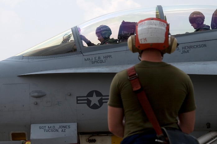 A flight crew Marine watches as Maj. Brad Hipp, Marine Fighter Attack Squadron (All Weather) 224 pilot training officer and the red team air mission commander, prepares to take off to participate in an interoperability flight training scenario as Exercise Cope Tiger 2009 progressed to its third day here March 11. During the training scenario, participating Cope Tiger aviation units are split into opposing red and blue teams in which the red team act out the aggressors.