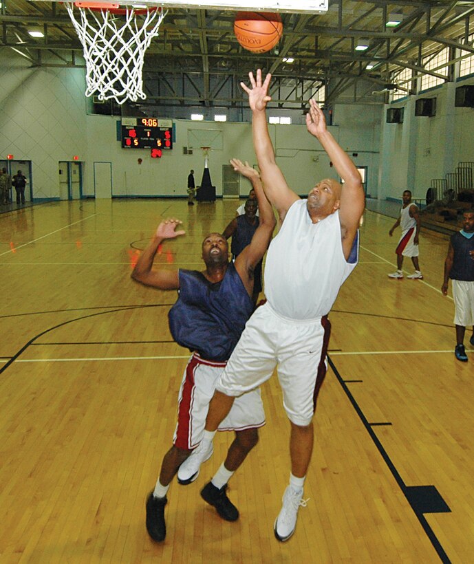 Keith McCauley, 316th Civil Engineer Squadron center, lays up two points against Mitchell Berry, Air National Guard Readiness Center guard, during an Over-30 championship game at the East Fitness Center Tuesday. The 316 CES team beat the ANGRC 60-30 to win the title. (U.S. Air Force photo/Bobby Jones)