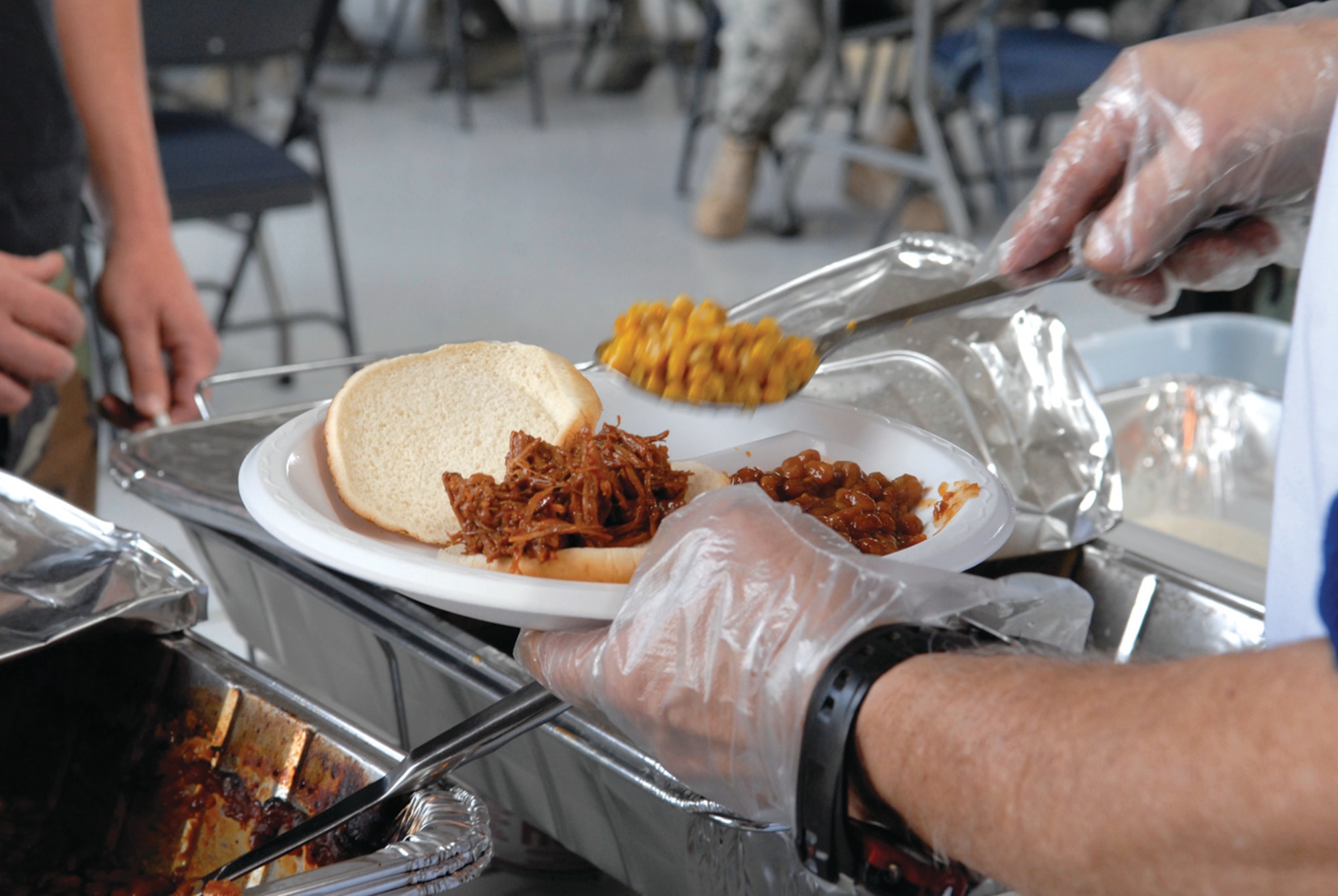 Carl Main serves buttered corn to an Airman at the feast. The meal on March 5 consisted of barbecue sandwiches, baked beans, salad, coleslaw, corn, chips, lemonade and cakes. (Deborah Silliman-Wolfe)