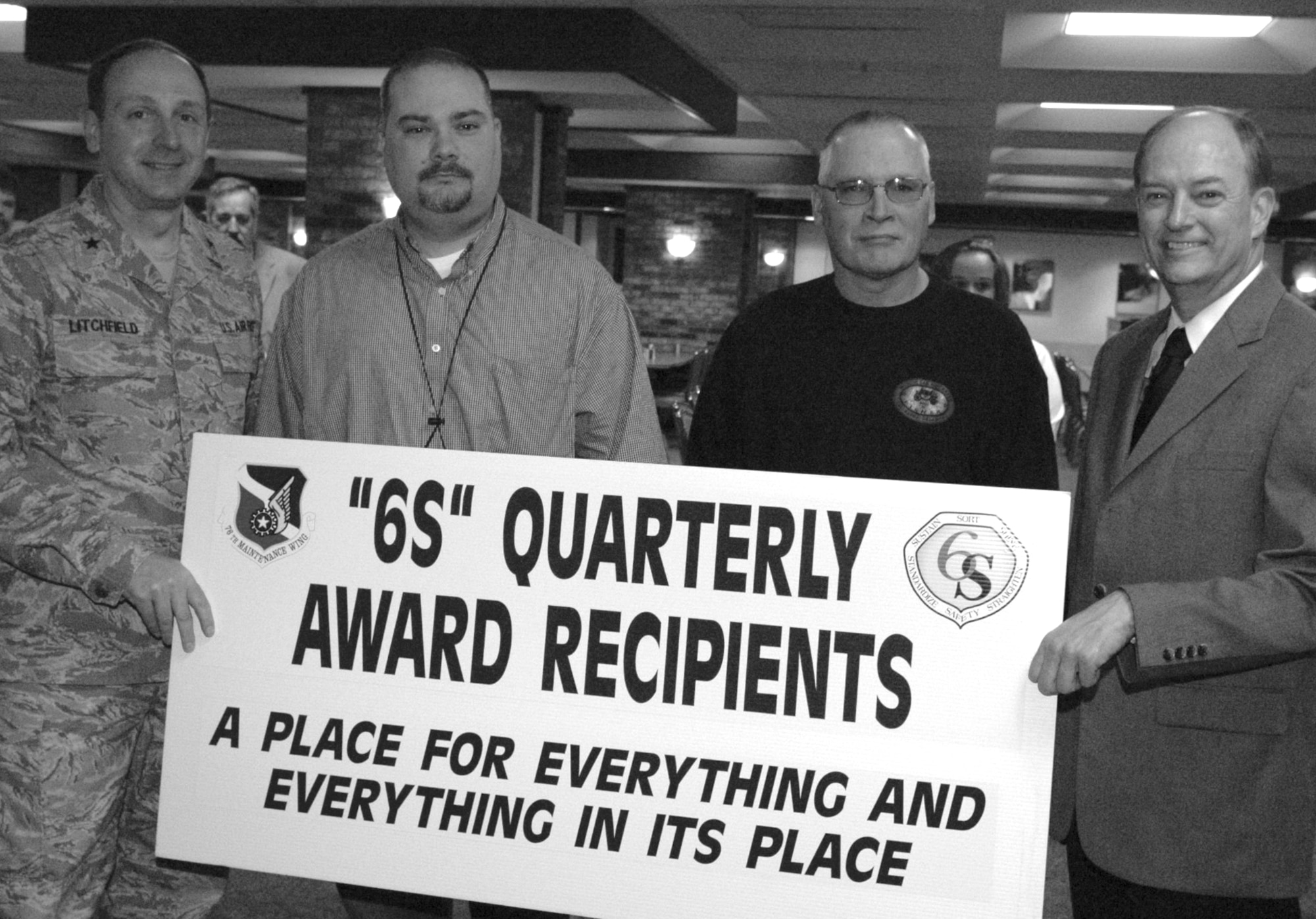 Brig. Gen. Bruce Litchfield, 76th Maintenance Wing commander, and James Patterson, 76th MXW deputy director, present one of three traveling 6S banners to Darrell Chambers and Jerry Wroblewski from the 566th Aircraft Maintenance Squadron Paint Parts and Equipment Storage work center at the 6S quarterly award ceremonies held March 3 at the base restaurant.  Evaluators awarded the work center 91 points out of 100. (Air Force photo by Ron Mullan)