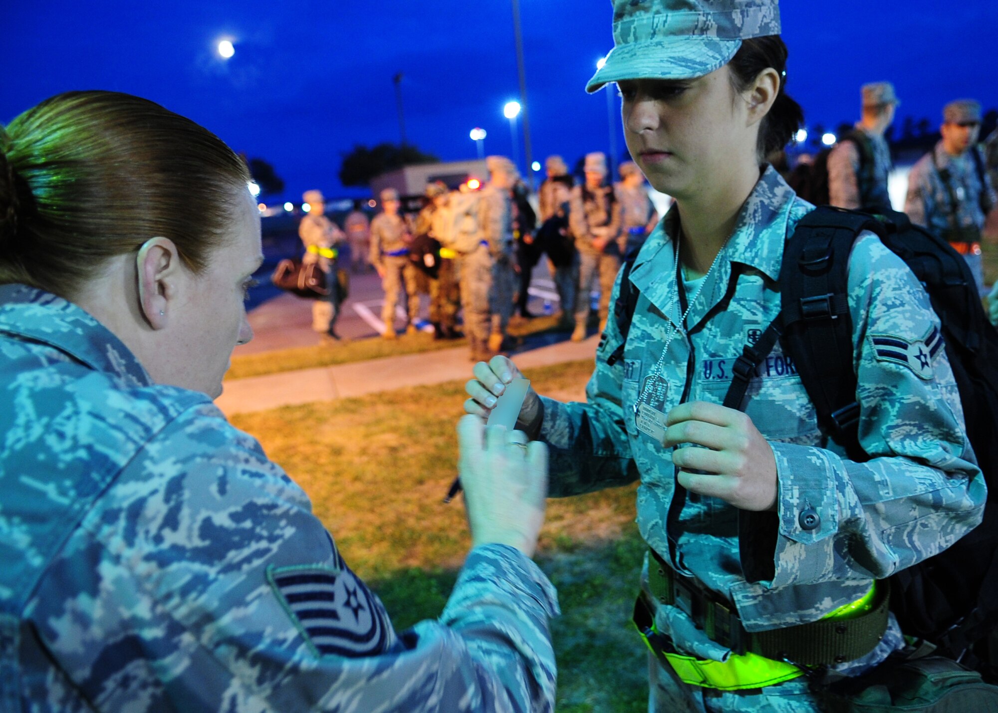 Airman 1st Class Cynthia Bindert, 4th Aerospace Medical and Dental Squadron, presents her military identification and dog tags to Tech. Sgt. Linda Sampson, 4th Force Support Squadron, prior to beginning a series of deployment-preparation briefings as part of a training exercise at Seymour Johnson Air Force Base, N.C., March 12, 2009. An operational readiness exercise has two phases. Phase one tests deployment preparation and mobilization, and phase two tests the ability to operate in a deployment-like environment. (U.S. Air Force photo by Airman 1st Class Rae A. Perry)