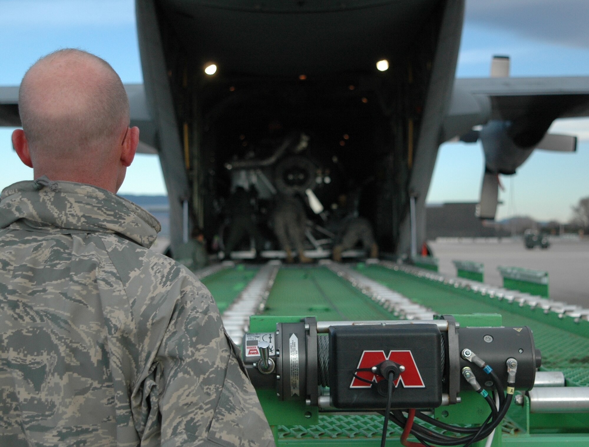 Master Sgt. Thomas Freeman looks on as members of the 302nd Airlift Wing work to offload a second-generation Military Airborne Firefighting System unit from its C-130 transport March 12, 2009, at Peterson Air Force Base, Colo. Known as MAFFS II, the unit augments the current MAFFS system, but is portable and self contained, making it more cost effective. Over time, MAFFS II will replace existing MAFFS units throughout the military's firefighting fleet supported by three Air National Guard wings as well as the Air Force Reserve's 302nd AW at Peterson. Sergeant Freeman is a loadmaster with the 731st Airlift Squadron. (U.S. Air Force photo/Senior Airman Stephen Collier)