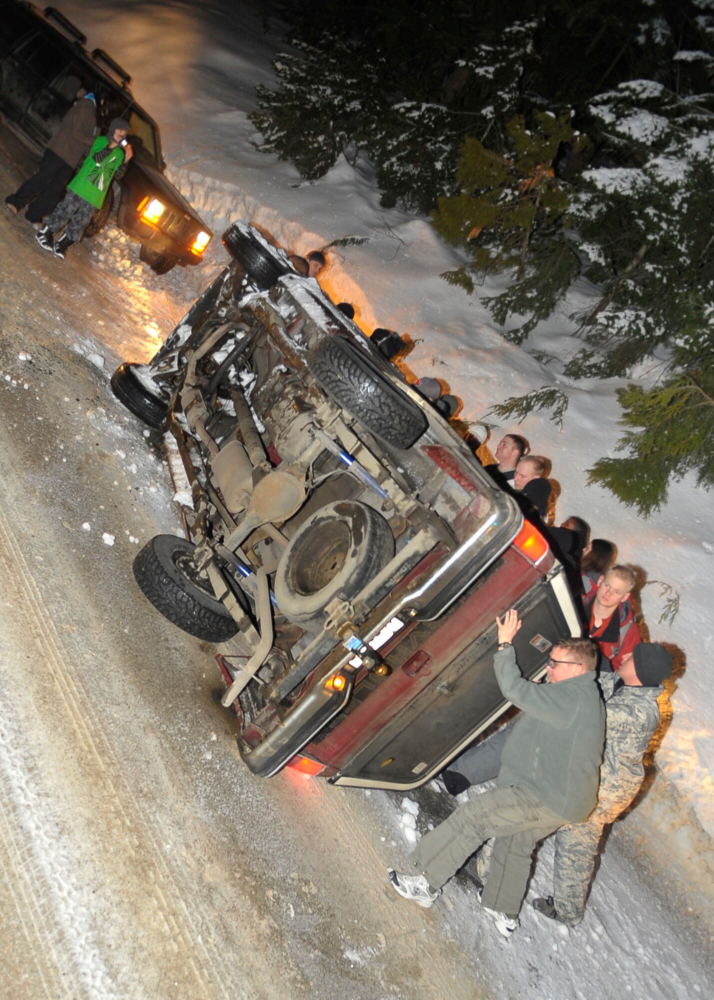 MEAD, Wash. – Nine Fairchild Airmen assist a local park ranger with turning a sports utility vehicle back on to it’s wheel base after the driver crashed into a sidewall and flipped his automobile near Mt. Spokane in Mead, Wash., Feb. 28. The nine Airmen were part of a group of 18 that were involved in a snow trip put together by the Fairchild‘s Base Chapel. (U.S. Air Force photo / Senior Airman Joshua K. Chapman)