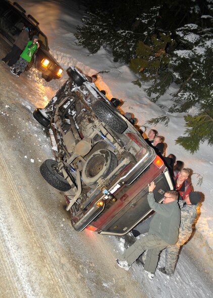 MEAD, Wash. – Nine Fairchild Airmen assist a local park ranger with turning a sports utility vehicle back on to it’s wheel base after the driver crashed into a sidewall and flipped his automobile near Mt. Spokane in Mead, Wash., Feb. 28. The nine Airmen were part of a group of 18 that were involved in a snow trip put together by the Fairchild‘s Base Chapel. (U.S. Air Force photo / Senior Airman Joshua K. Chapman)