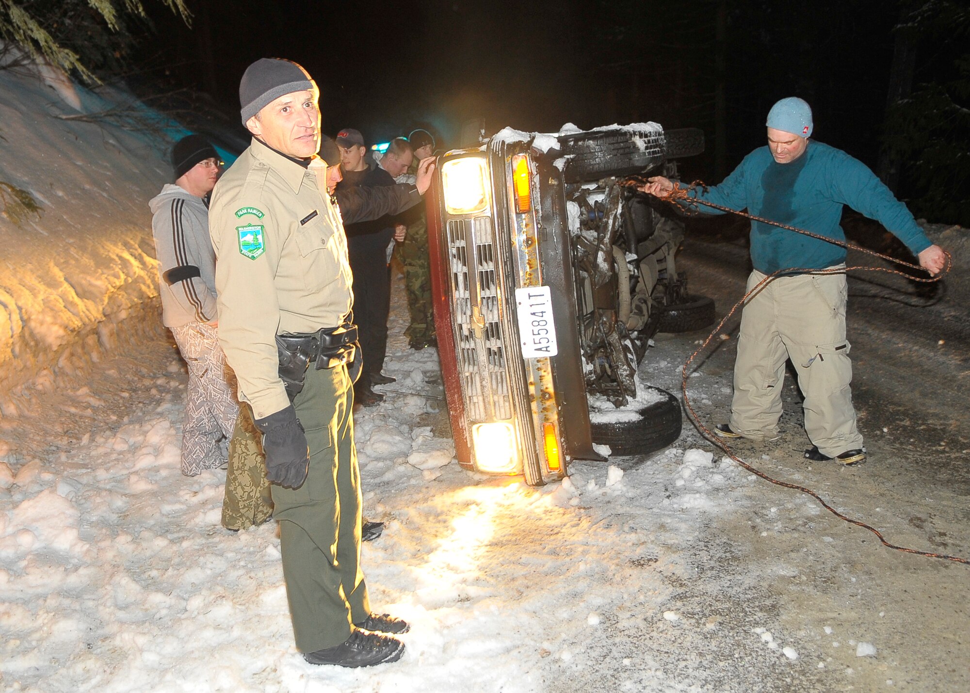 MEAD, Wash. – A Mt. Spokane park ranger from Mead, Wash., coordinates the efforts of nine Fairchild Airmen as they assist a man with flipping his truck back onto its axels near Mt. Spokane Feb. 28. Within five minutes the Airmen flipped the truck successfully and the man continued on his way home. (U.S. Air Force photo / Senior Airman Joshua K. Chapman)