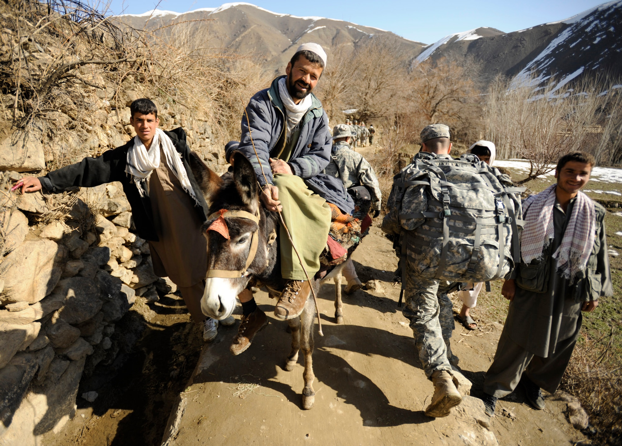 Army Sgt. Ramon Guzman walks past villagers during a March 5 site visit in Afghanistan's Panjshir Valley. Sergeant Guzman is a Panjshir Provincial Reconstruction Team civil affairs member. (U.S. Air Force photo/Staff Sgt. James L. Harper Jr.)