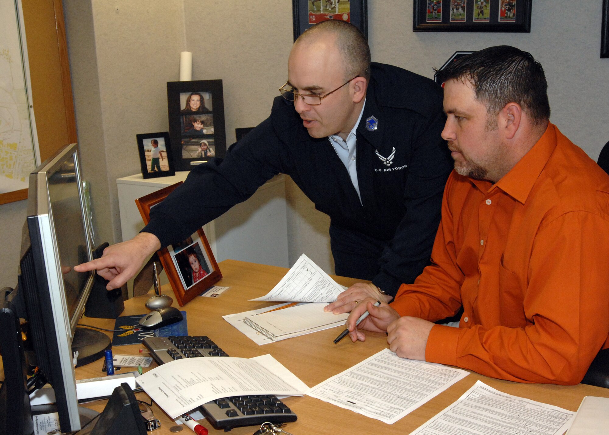 Dean Burson, 100th Communications Squadron chief of infrastructure, goes over an enlisted performance report with Senior Master Sgt. Michael Lioce, 100th Communications Squadron Operations Flight chief. Mr. Burson is the 100th Air Refueling Wing Annual Award winner in the Civilian Supervisor category and will be competing at United States Air Forces in Europe command level for the third year in a row. (U.S Air Force photo by Senior Airman Teresa M. Hawkins)
