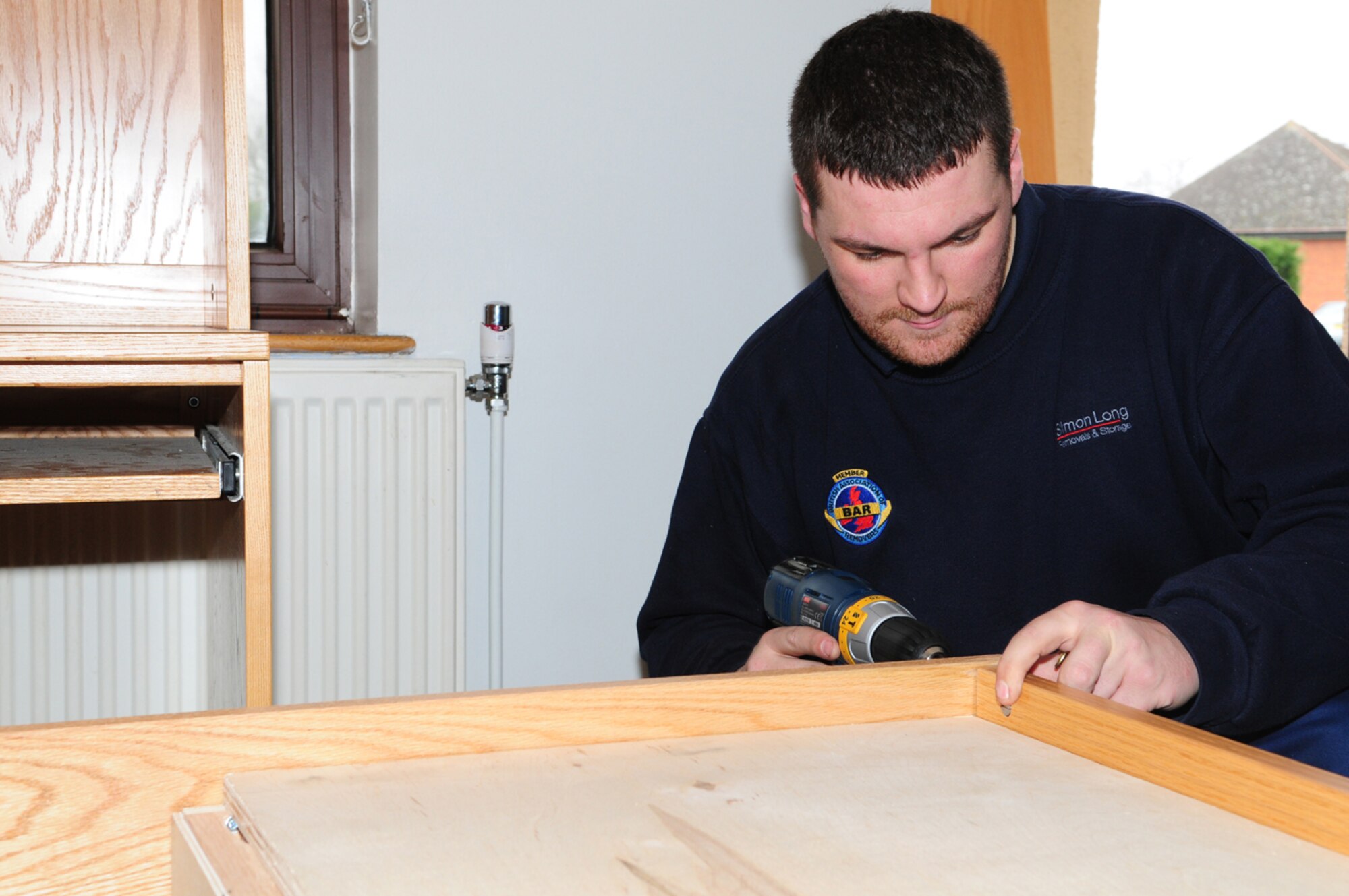 Steward Armstrong, a local contractor, puts together a bed in Dorm 210. The company brought in and put together beds and other furniture in dorms on RAFs Mildenhall and Lakenheath as part of an ongoing quality of life project. (U.S. Air Force photo by Karen Abeyasekere)