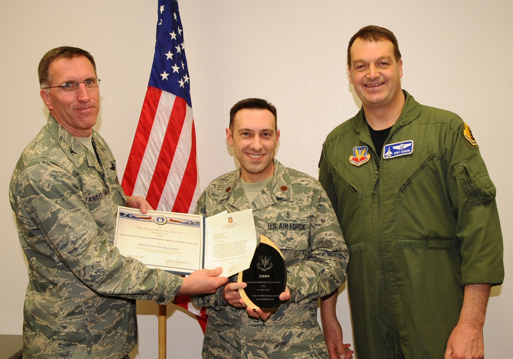 Maj. Stephen Boglarski (center), 28th Medical Operations Squadron operational health flight commander, receives the Air Force's and Air Combat Command's Outstanding Field Grade Base Bioenvironmental Engineer of the Year from Col. Scott Vander Hamm (left), 28th Bomb Wing commander, and Col. Kory Cornum (right), ACC surgeon general. The awards recognize Ellsworth healthcare providers in a range of specialties, ranks and accomplishments; many of whom spearheaded important programs, changes in their sections and volunteered their time to the local community. (U.S. Air Force photo/Senior Airman Kasey Zickmund)