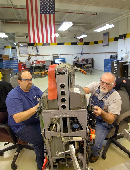 Jeff Hand and Stan Jackson put a B-1B Lancer seat back together after preventive maintenance March 2 at Tinker Air Force Base, Okla. Each seat holds 14 miniature explosive devices that synchronize in an emergency to help propel a strapped-in crew member from a doomed aircraft at zero to 80 mph in approximately two seconds. (U.S. Air Force photo/Margo Wright) 