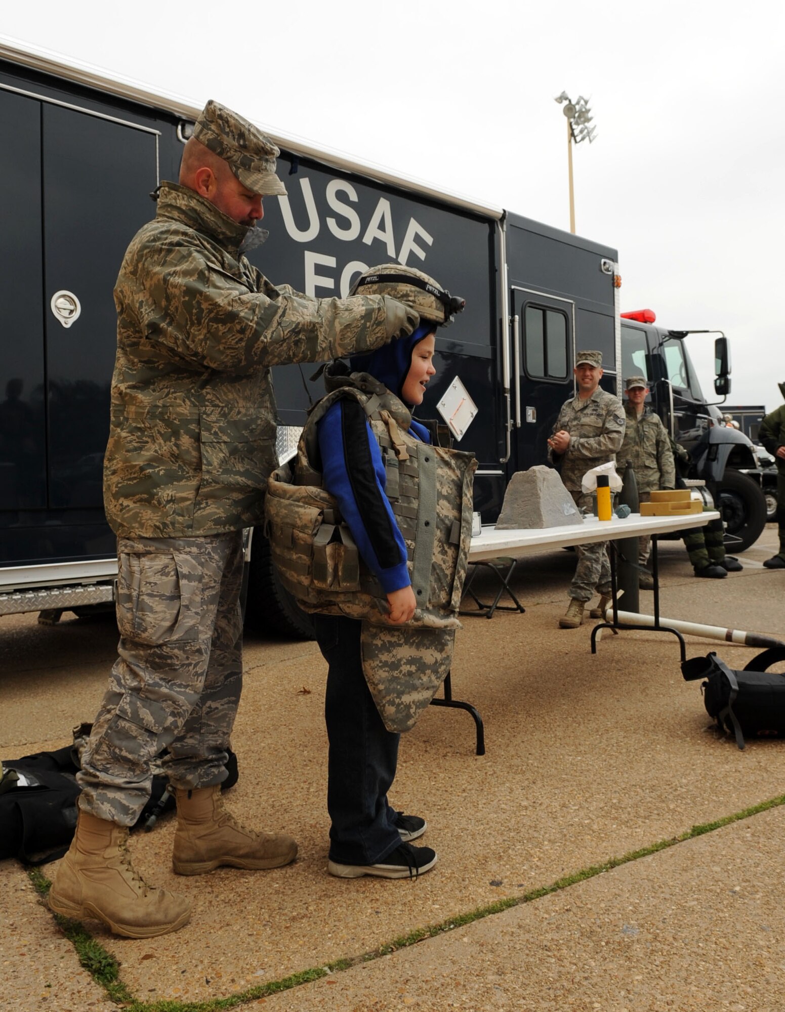 Branden Meeks, son of Master Sgt. Brian Meeks, 608th Air Force Network OPerations Center, tries on equipment at the 2d Force Support Squadron's Explosive Ordnance Disposal display.(Airman 1st Class Brittany Y. Bateman/U.S. Air Force)