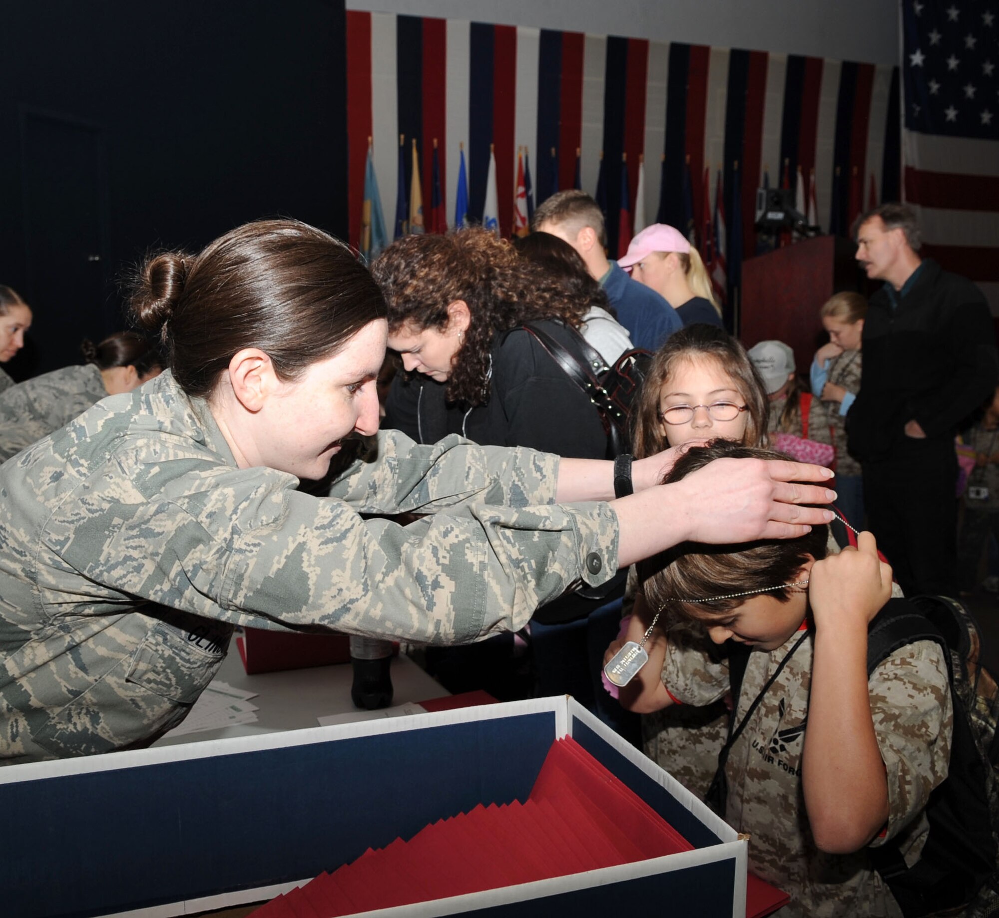Capt. Kathryn Gilno, 2d Force Support Squadron, places dog tags around Taelin Villarreal, 9, son of Tech Sgt. Chris Deane, Airmen and Family Readiness Center readiness noncommissioned officer. (Airman 1st Class Brittany Y. Bateman/U.S. Air Force)