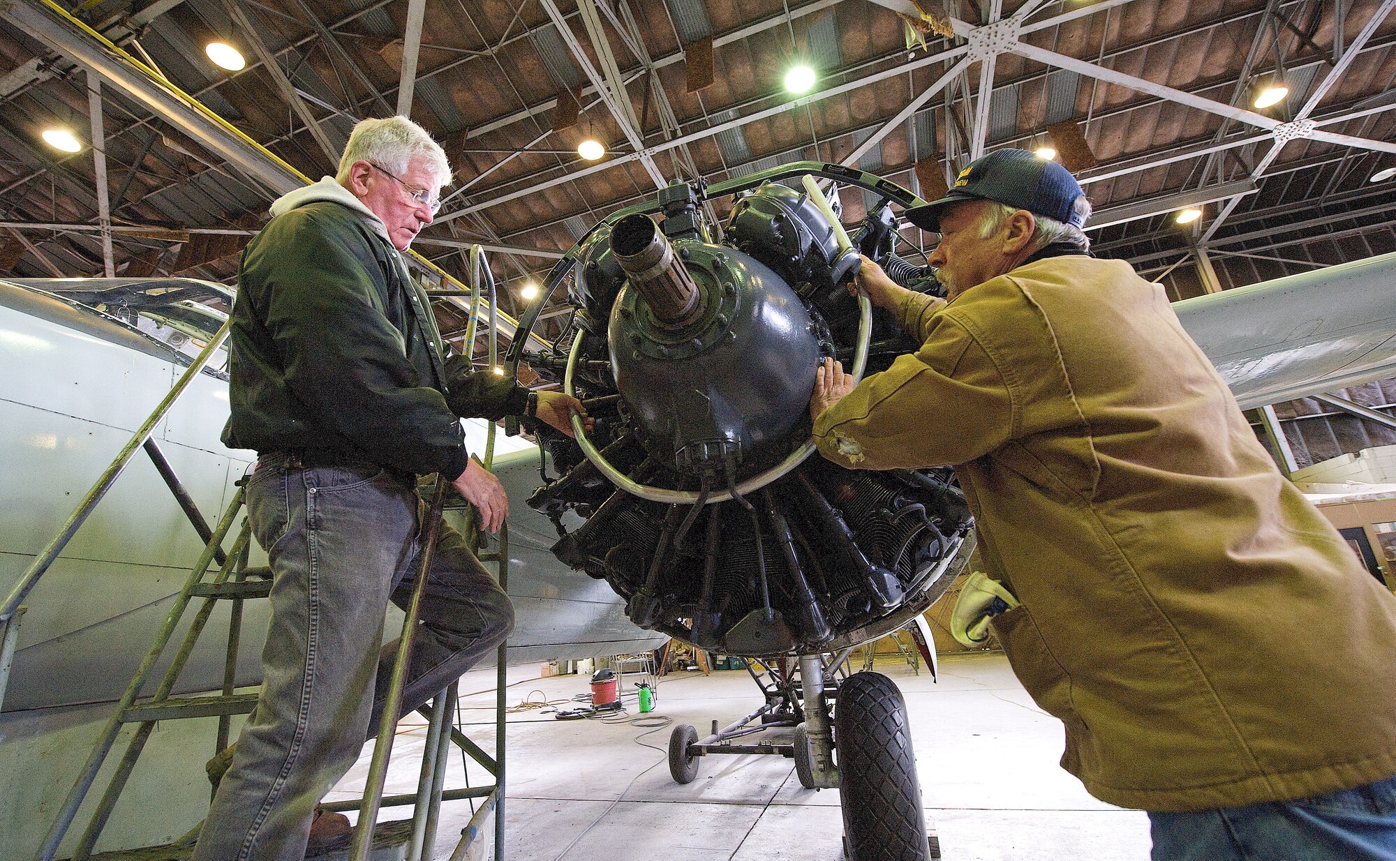 (From left) Sandy Sandstrom and Gary Burris, Air Mobility Command Museum volunteers, install a simulated ignition coil on an A-26 Invader engine.  Mr. Sandstrom and Mr. Burris are part of a group of volunteers who repair aircraft for display at the AMC Museum.  (U.S. Air Force photo/Jason Minto)