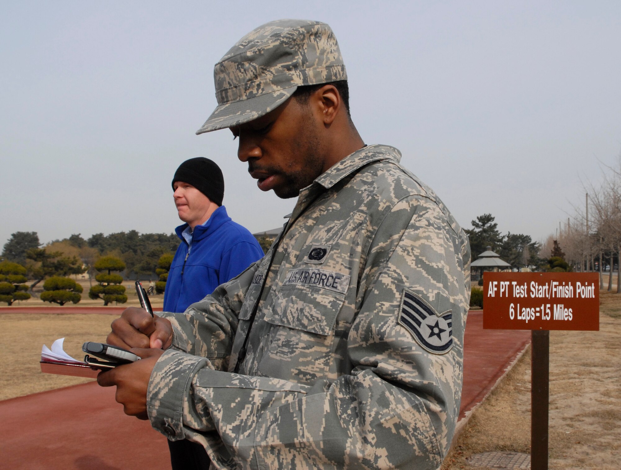 Staff Sgt. Lavarr Walker, 8th Maintenance Group, and Exercise Physiologist William Goins, from the Health and Wellness Center evaluate members during the 1.5 mile run portion of the physical fitness test at Kunsan Air Base, Republic of Korea, March 12, 2009. Sergeant Walker is one of the augmented phyisical training leaders helping the HAWC with the new centralized physical testing policy. ( U.S. Air Force photo by: Senior Airman Dana Hill)