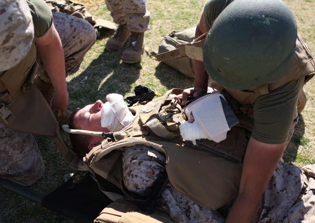 Pfc. Henry Lopez, a Combat Lifesaver student, performs a final check on his simulated casualty prior to transport March 13 at Victory Field. Students had to properly treat and evacuate casualties to pass the final test.