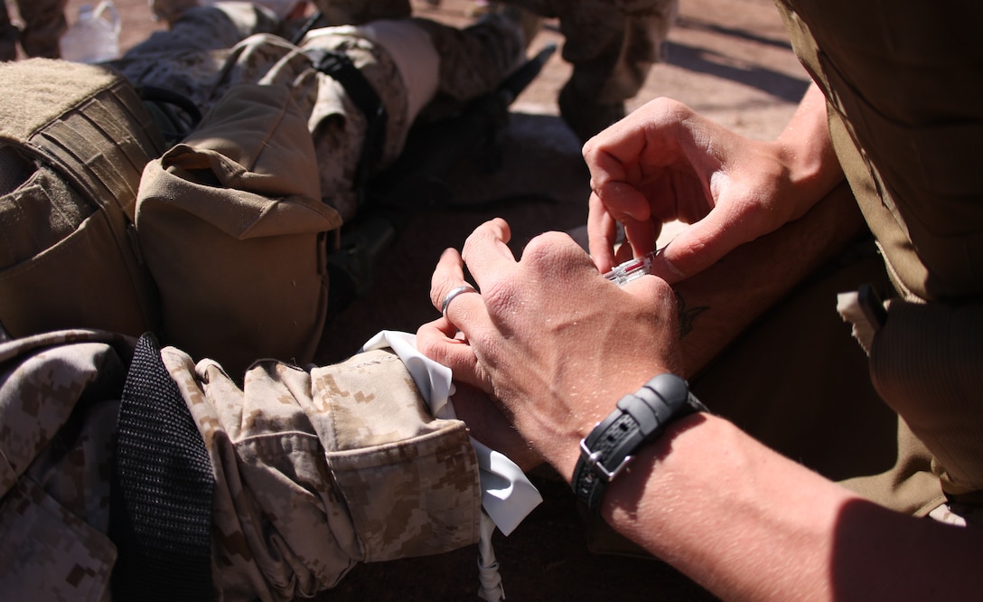 A student in the Combat Lifesaver course inserts and intravenous tube, or IV, into his simulated casualty March 13 at Victory Field. After a simulated severing of his leg, it was determined that his casualty would have lost a great deal of blood and needed an IV to replenish his bodily fluids.
