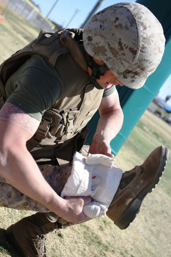 Pfc. Robert McCabe, a student in the Combat Lifesaver course, applies a bandage to his simulated casualty during the final test March 13 at Victory Field.