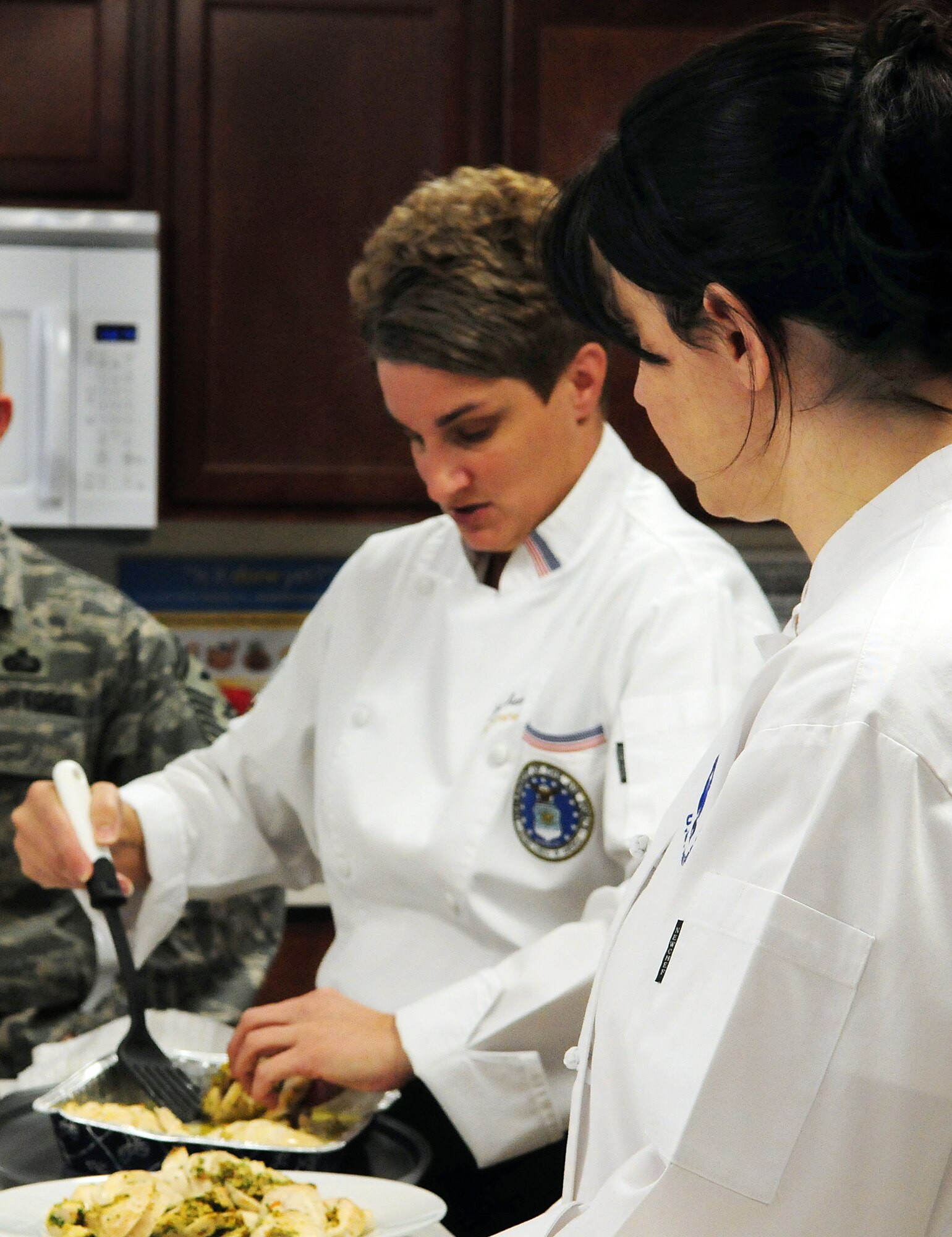Master Sgt. Jamie Green and Tech. Sgt. Teresa Vanderford (close), both general officer enlisted aides, demonstrate cooking techniques for Airmen at the United States Air Force Honor Guard dormitory March 12. The recipes demonstrated included chicken cordon bleu and poached rolled chicken with parsley and tarragon. These classes are held monthly and teach Airmen how to shop, handle and prepare their own meals. “We’re doing this to instruct these young Airmen in the basics of food preparation and menu handling so they have a healthy alternative to fast food,” said Sergeant Vanderford. (U.S. Air Force photo by Airman 1st Class Susan Moreno)
