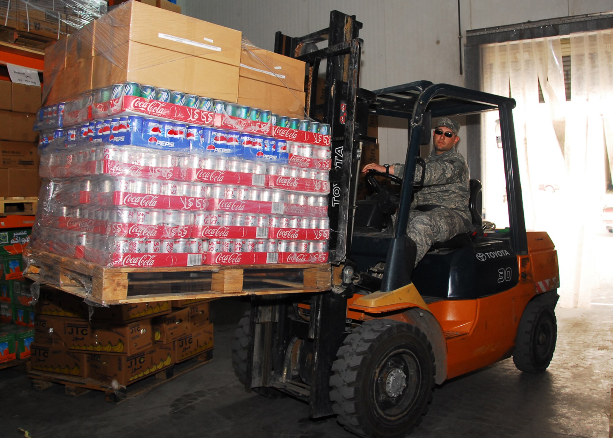SOUTHWEST ASIA -- Tech. Sgt. Don Cota, 386th Expeditionary Force Support Squadron, transfer's beverages from the delivery truck to a warehouse-size refrigerator at an air base in Southwest Asia, March 13. The mission of the Rations operation, shared with a local contractor in the form of Assistance-in-Kind services, is to provide quality meals to all U.S. and Coalition warfighters on the base. Sergeant Cota is currently deployed from Altus Air Force Base, Okla.,and is originally from Ogdensburg, N.Y.(U.S. Air Force photo/Senior Airman Courtney Richardson)