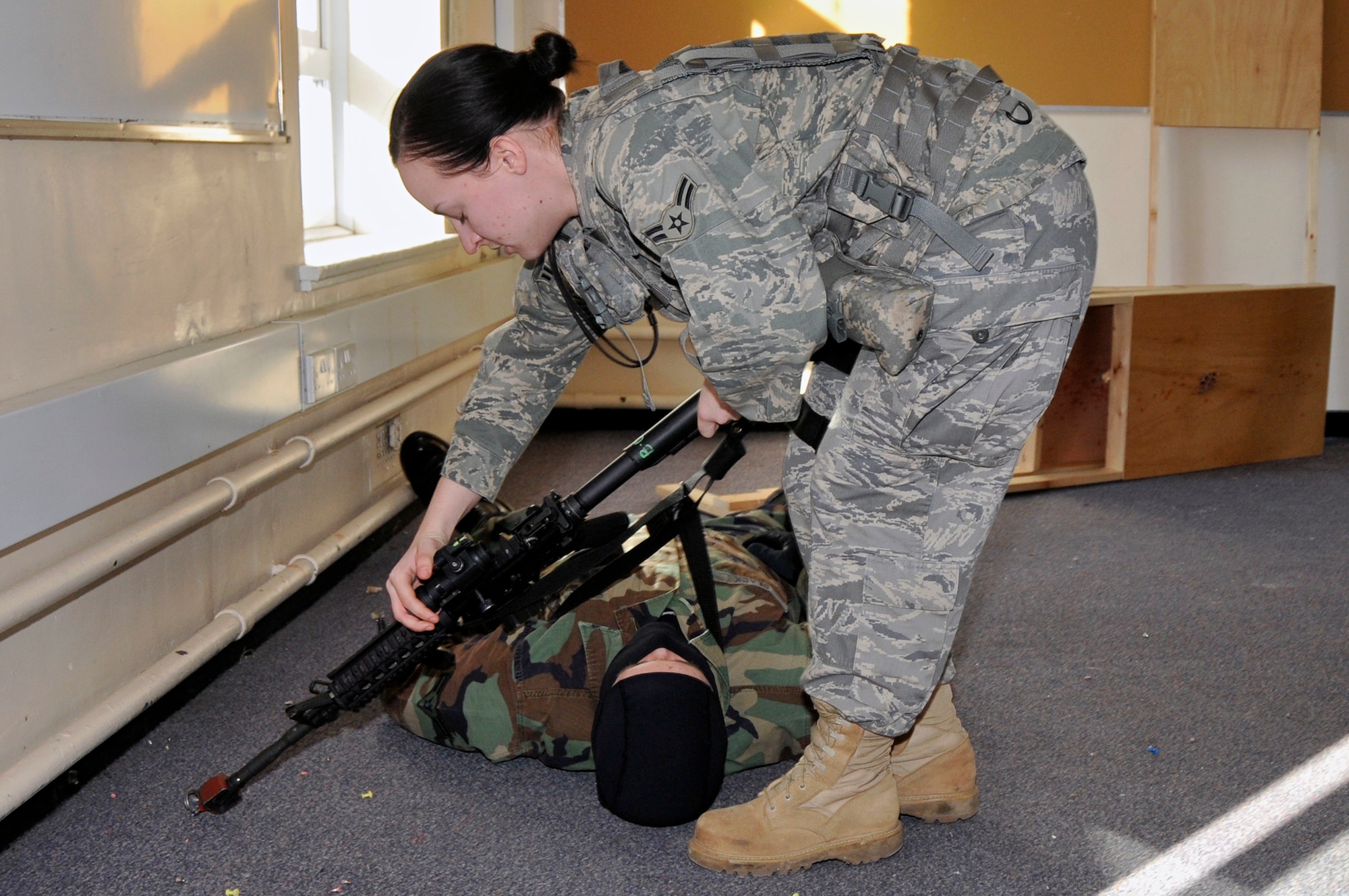 After subduing a simulated gunman, Airman 1st Class Kristen Brousseau, 48th Security Forces Squadron disarms the gunman March 4, 2009 at RAF Feltwell, England. The Airmen are participating in a "Active Shooter" scenario which teaches security forces Airmen how to handle a school shooting. (U.S. Air Force photo by Airman 1st Class Perry Aston)