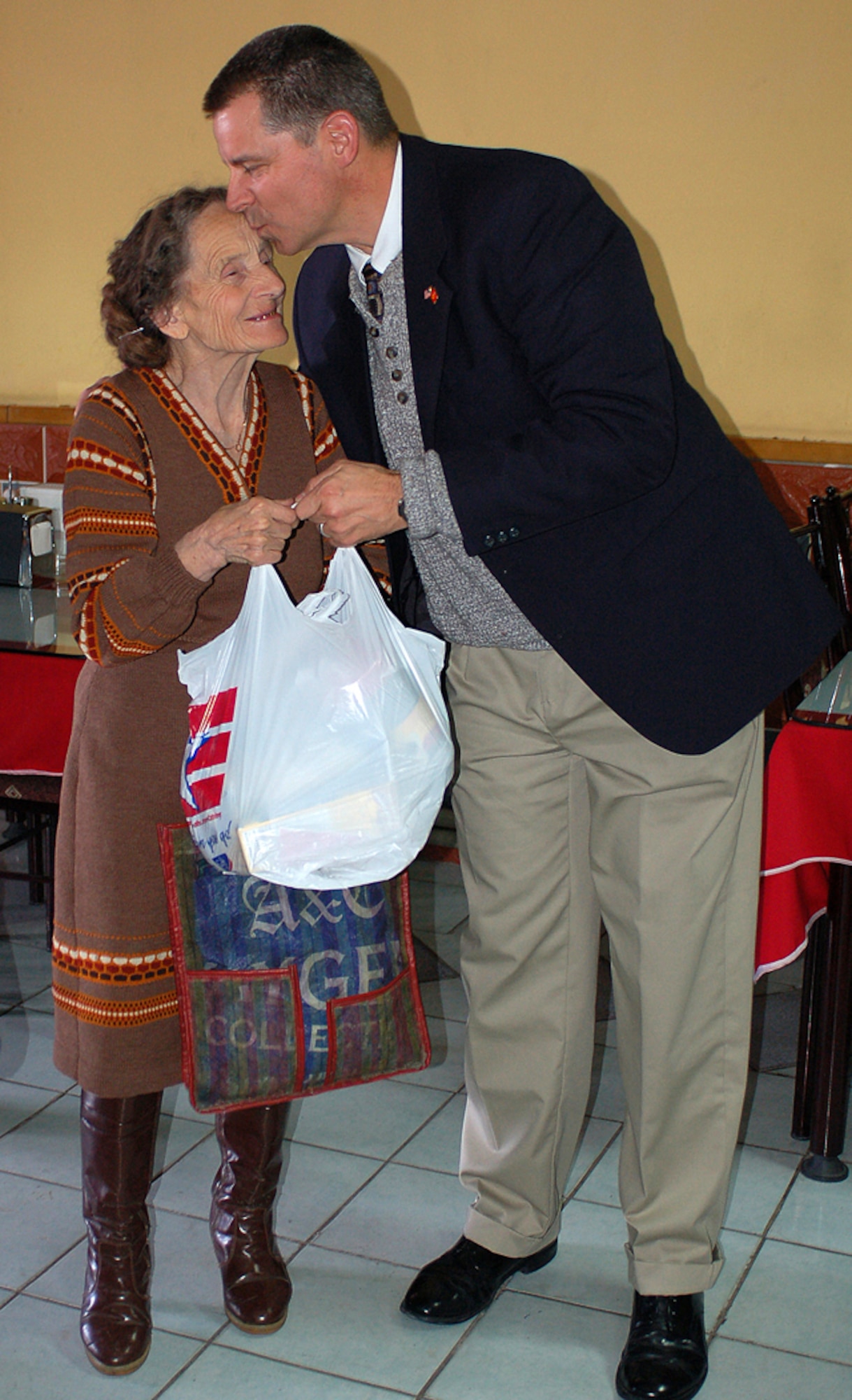 Manas Air Base Outreach Society member, Col. (Dr.) Gerry Caron, kisses Vera Wolf goodbye and gives her a bag of foodstuff and toiletries at a Turkish restaurant in Bishkek, Kyrgyzstan, March 9. Vera is known as a Babushka, or elderly woman, in Russian and Kyrgyz cultures. The 78-year-old woman has no family and was ?adopted,? along with two other elderly women, by MABOS through the Babushka Adoption Foundation, a local non-governmental organization. Each lady?s monthly income averages about 700 som or around $20 per month. Every month, volunteers from Manas join the ladies for lunch to share companionship, a little financial support and a small supply of groceries. Colonel Caron is the 376th Expeditionary Medical Group commander and is deployed from the Headquarters Air Education and Training Command where he is the deputy command surgeon. (U.S. Air Force photo/Tech. Sgt. Elizabeth Weinberg)