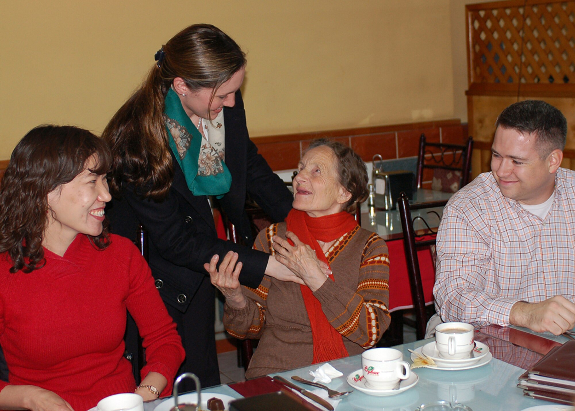 Captain Jamie Fanning (standing) gives Vera Wolf a new scarf while Kyrgyz translator Janyl Sabirova and Maj. Glenn Donnelly look on during a lunch visit with Manas Air Base Outreach Society members at a Turkish restaurant in Bishkek, Kyrgyzstan, March 9. Vera is known as a Babushka, or elderly woman, in Russian and Kyrgyz cultures. The 78-year-old woman has no family and was ?adopted,? along with two other elderly women, by MABOS through the Babushka Adoption Foundation, a local non-governmental organization. Each lady?s monthly income averages about 700 som or around $20 per month. Every month, volunteers from Manas join the ladies for lunch to share companionship, a little financial support and a small supply of groceries. Captain Fanning, Major Donnelly and Ms. Sabirova are assigned to the 376th Expeditionary Medical Group. Captain Fanning is a sexual assault response coordinator deployed from the 52nd Fighter Wing at Spangdahlem Air Base, Germany. Major Donnelly is deployed from the 2nd Aerospace Medicine Squadron at Barksdale Air Force Base, La. (U.S. Air Force photo/Tech. Sgt. Elizabeth Weinberg)