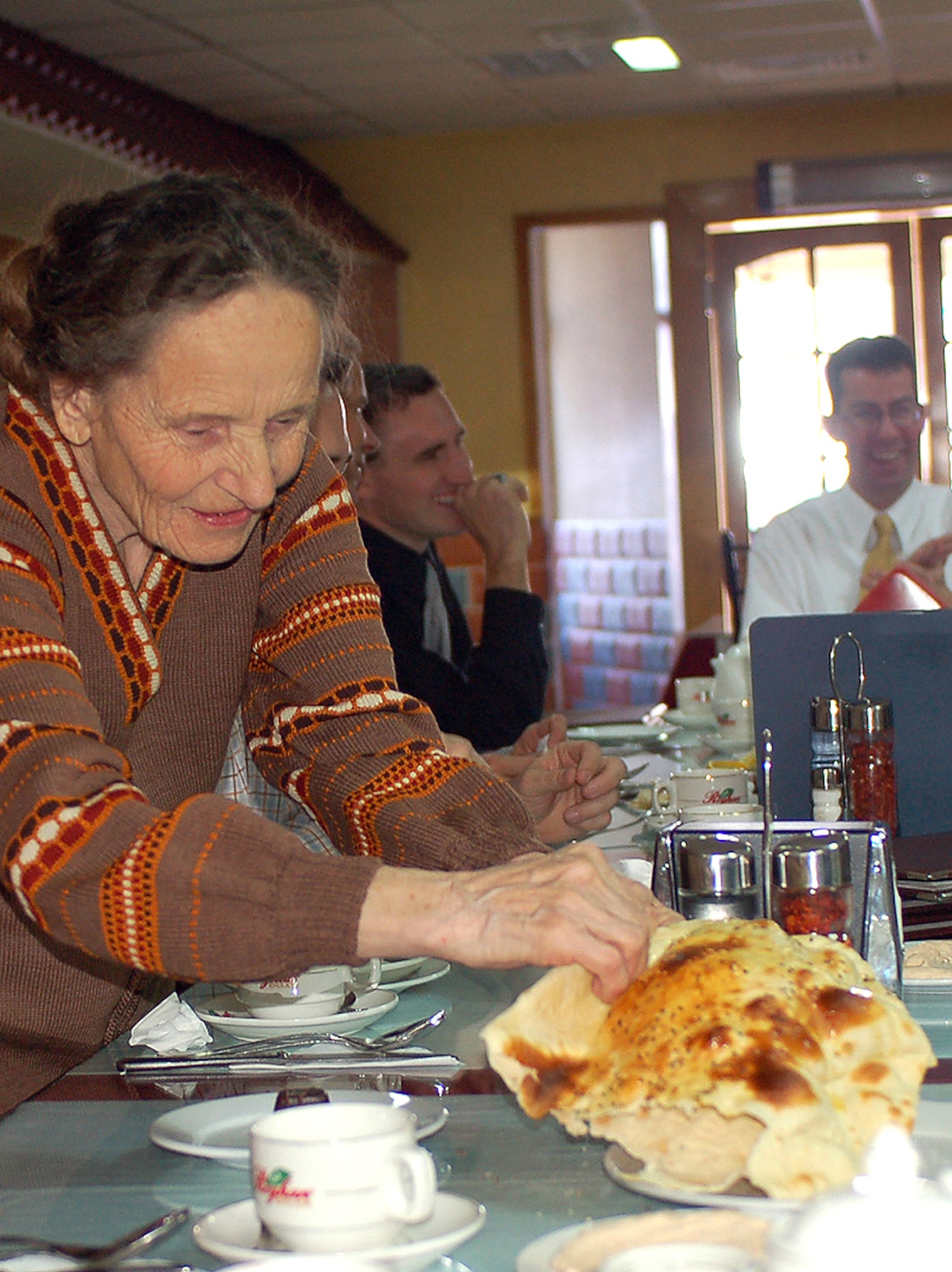 Vera Wolf tears off a piece of nan, a type of Kyrgryz bread, during a lunch visit with Manas Air Base Outreach Society volunteers March 9 at a Turkish restaurant in Bishkek, Kyrgyzstan. Vera is known as a Babushka, or elderly woman, in Russian and Kyrgyz cultures. The 78-year-old woman has no family and was ?adopted,? along with two other elderly women, by MABOS through the Babushka Adoption Foundation, a local non-governmental organization. Each lady?s monthly income averages about 700 som or $20 per month. Every month, volunteers from Manas join the ladies for lunch to share companionship, a little financial support and a small supply of groceries. (U.S. Air Force photo/Tech. Sgt. Elizabeth Weinberg)