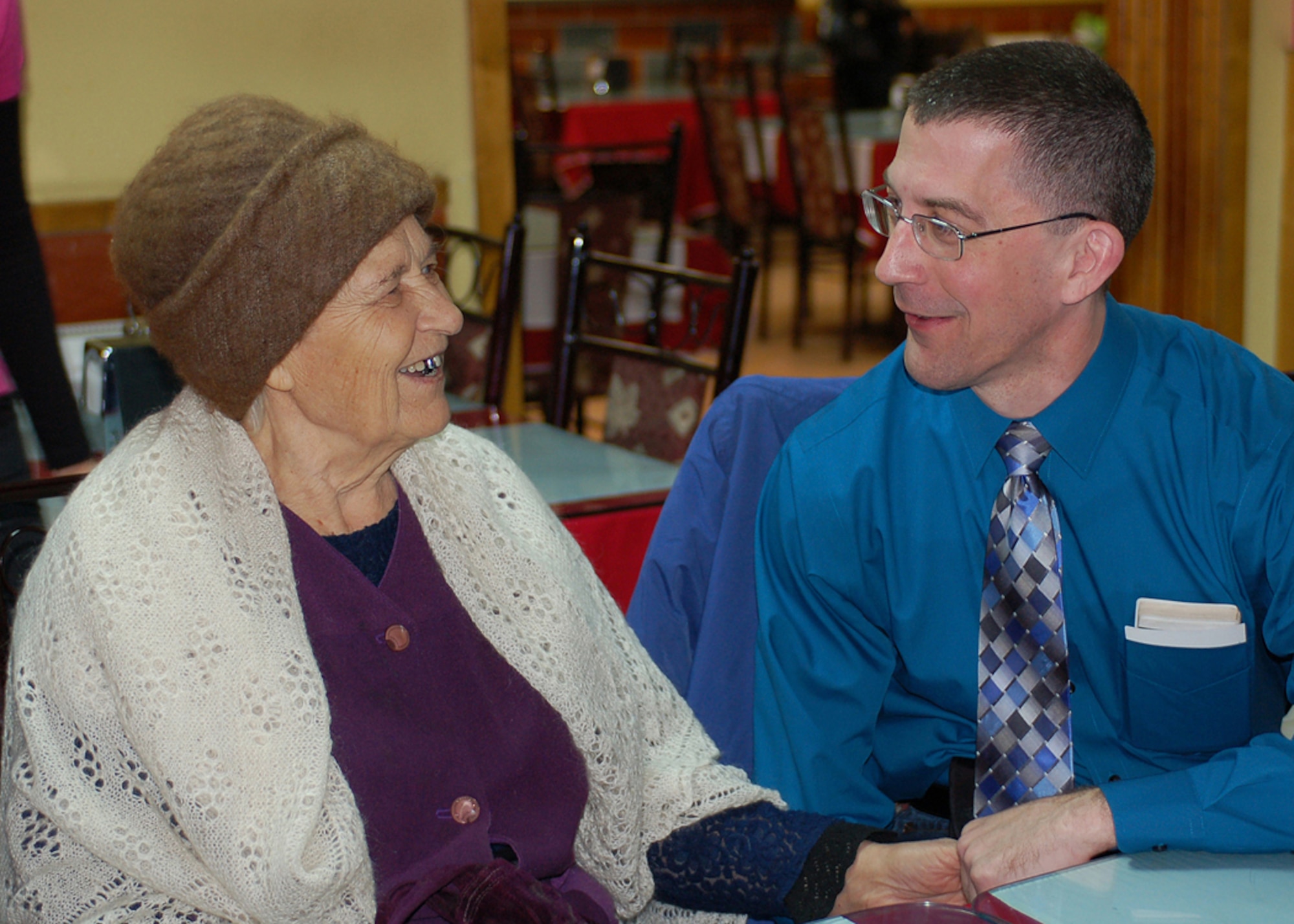 Chaplain (Maj.) Derek Wolter shares a conversation with Mariya Ruhlova at a Turkish restaurant March 9 in Bishkek, Kygryzstan. Mariya is known as a Babushka, or elderly woman, in Russian and Kyrgyz cultures. The 79-year-old woman has no family and was adopted, along with two other elderly women, by the Manas Air Base Outreach Society through the Babushka Adoption Foundation, a local non-governmental organization. Each lady's monthly income averages about 700 som or $20 per month. Every month, volunteers from Manas join the ladies for lunch to share companionship, a little financial support and a small supply of groceries. Chaplain Wolter is assigned to the 376th Air Expeditionary Wing Chaplain Office and is deployed from the Missouri Air National Guard's 131st Fighter Wing in St. Louis. (U.S. Air Force photo/Tech. Sgt. Elizabeth Weinberg)