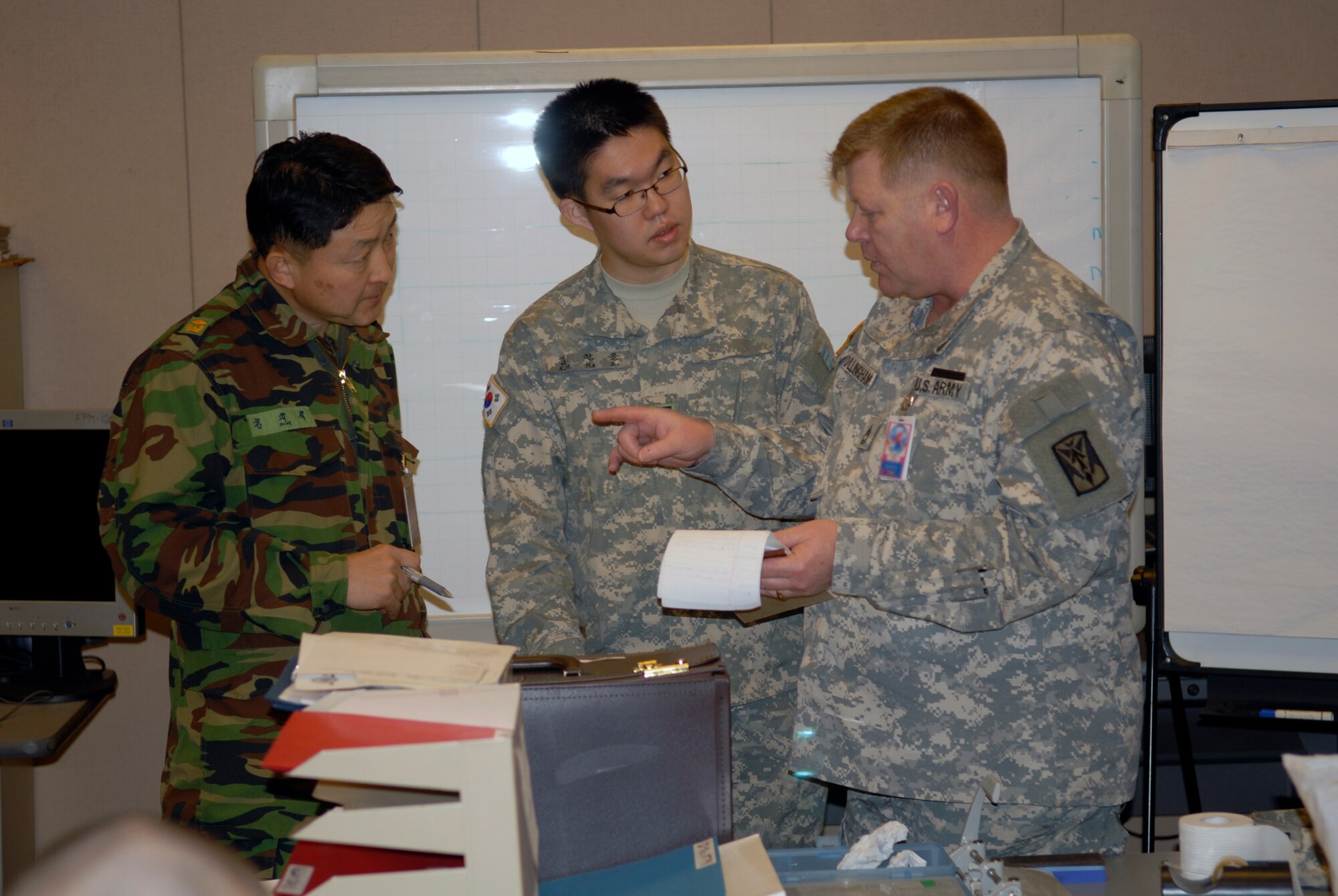 OSAN AIR BASE, Republic of Korea --  (Left to right) Republic of Korea Warrant Officer Kim, Jisik, Korean Augmentation Troop to the U.S. Army Corp. Kim, Hansol, and U.S. Army Sgt. 1st Class Thomas Dillingham discuss the roles of everyone in the U.S. “White Cell” during the Key Resolve/Foal Eagle exercise here March 9. The exercise demonstrates U.S. commitment to the ROK/U.S. Alliance and enhances combat readiness of ROK and U.S. supporting forces through combined and joint training. (U.S. Air Force photo by Staff Sgt. Benjamin Rojek)
