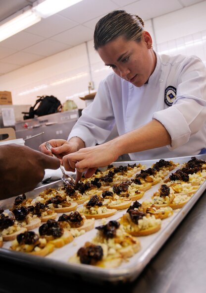 Tech. Sgt. Heather Gray, enlisted aide to Brig. Gen. Brett Williams, 18th Wing commander, prepares a dish in the officers' club kitchen at Kadena Air Base, Japan March 9. Team Kadena food service professionals are learning from Chef Dean Nole, who is sharing his talents here for two weeks. (U.S. Air Force photo/Airman 1st Class Chad Warren) 