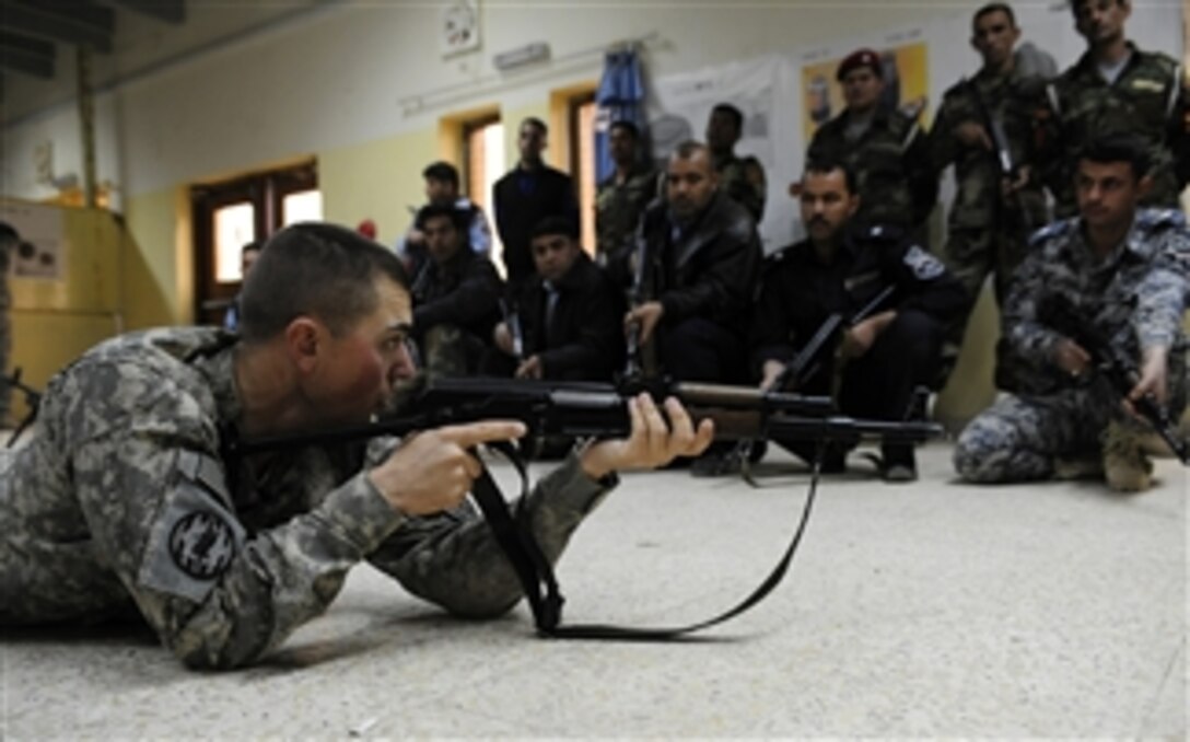 U.S. Army Cpl. Douglas Scott, a member of the 978th Military Police Company, 93rd Military Police Battalion, demonstrates the prone shooting position to Iraqi soldiers and Iraqi policemen during a weapons training class at Joint Security Station 402 in Kadhimiya, Iraq, on March 1, 2009.  
