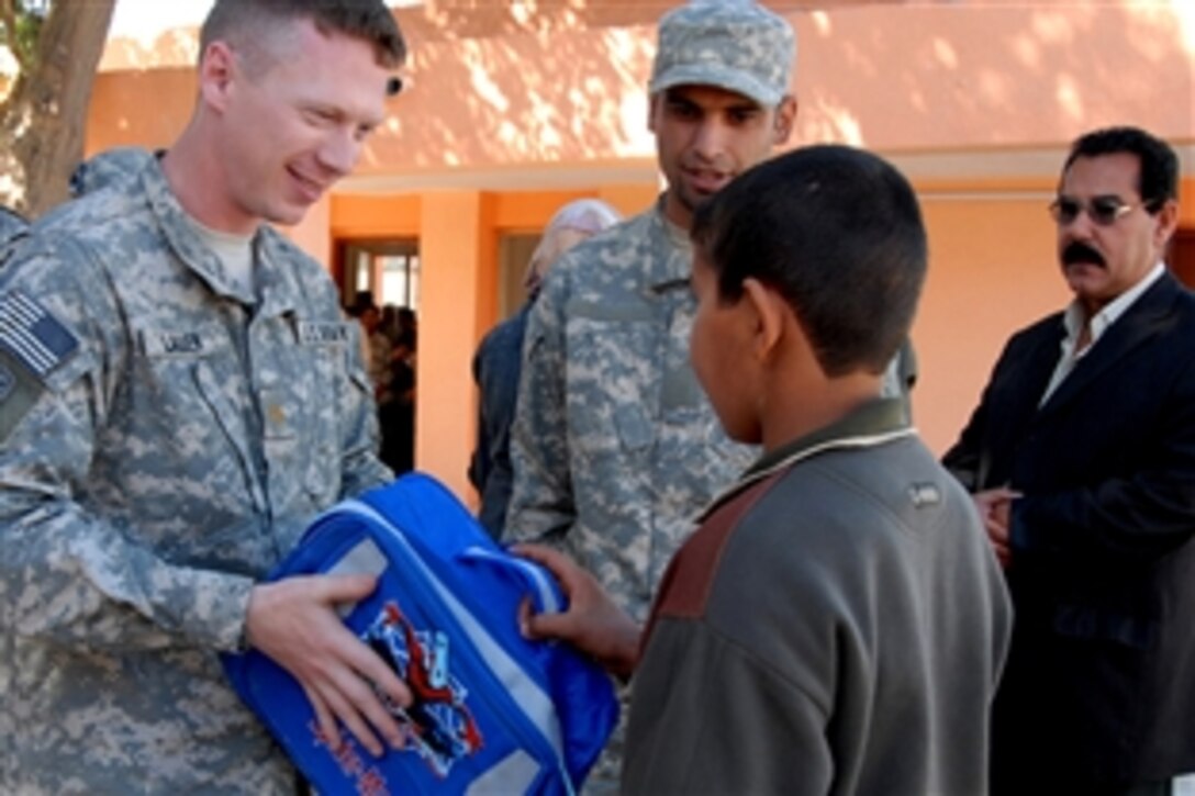 U.S. Army Maj. Ian Lauer, left, presents an Iraqi student  with a backpack at a school in Tunis, Iraq, March 12, 2009. Lauer is assigned to Troop E, 5th Calvary Regiment, 172nd Infantry Brigade.