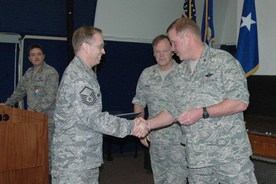 Master Sgt. Randy Merritt, 919th Special Operations Wing Comptroller's office, receives congratulations from Brig. Gen. Mark Kyle, Air Force Reserve Command inspector general, during the Unit Compliance Inspection outbrief March 10 in Spectre Hall.  Sergeant Merritt was one of the wing's 13 superior performers recognized at the conclusion of the week-long inspection.  Behind them is Col. Jon Berrie, UCI team chief.