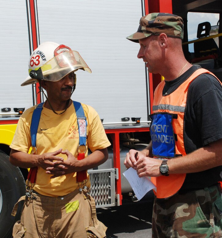SOTO CANO AIR BASE, Honduras - Joint Task Force-Bravo firefighter Master Sgt. Pat Miller consults with Comayagua Deputy Fire Chief Lt. Jorge Turcias on a plan to safely recover an overturned fuel truck on C.A. 5 Friday.  The truck overturned approximately 8 kilometers north of the base after hitting a horse around 8 a.m.  (U.S. Air Force photo/Tech. Sgt. Rebecca Danét)