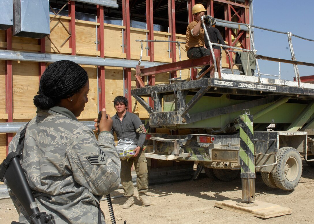 Senior Airman LaQuanna Pittman, 455th Expeditionary Civil Engineer Squadron force protection flight, escorts third country nationals as well as local workers at Bagram Air Field, Afghanistan, March 12. TCN and local workers are builiding an extension to the flightline for the 455th Expeditionary Maintenance Group, which will allow more office and work space. There are approximately 70 Airmen that escort anywhere from 75 to 100 TCN's on any given day. Airmen Pittman is deployed from Andrews Air Force Base, Md. and hales from Gulfport, Miss. (U.S. Air Force photo/ Senior Airman Erik Cardenas)(Released)