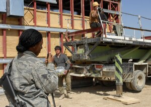 Senior Airman LaQuanna Pittman, 455th Expeditionary Civil Engineer Squadron force protection flight, escorts third country nationals as well as local workers at Bagram Air Field, Afghanistan, March 12. TCN and local workers are builiding an extension to the flightline for the 455th Expeditionary Maintenance Group, which will allow more office and work space. There are approximately 70 Airmen that escort anywhere from 75 to 100 TCN's on any given day. Airmen Pittman is deployed from Andrews Air Force Base, Md. and hales from Gulfport, Miss. (U.S. Air Force photo/ Senior Airman Erik Cardenas)(Released)