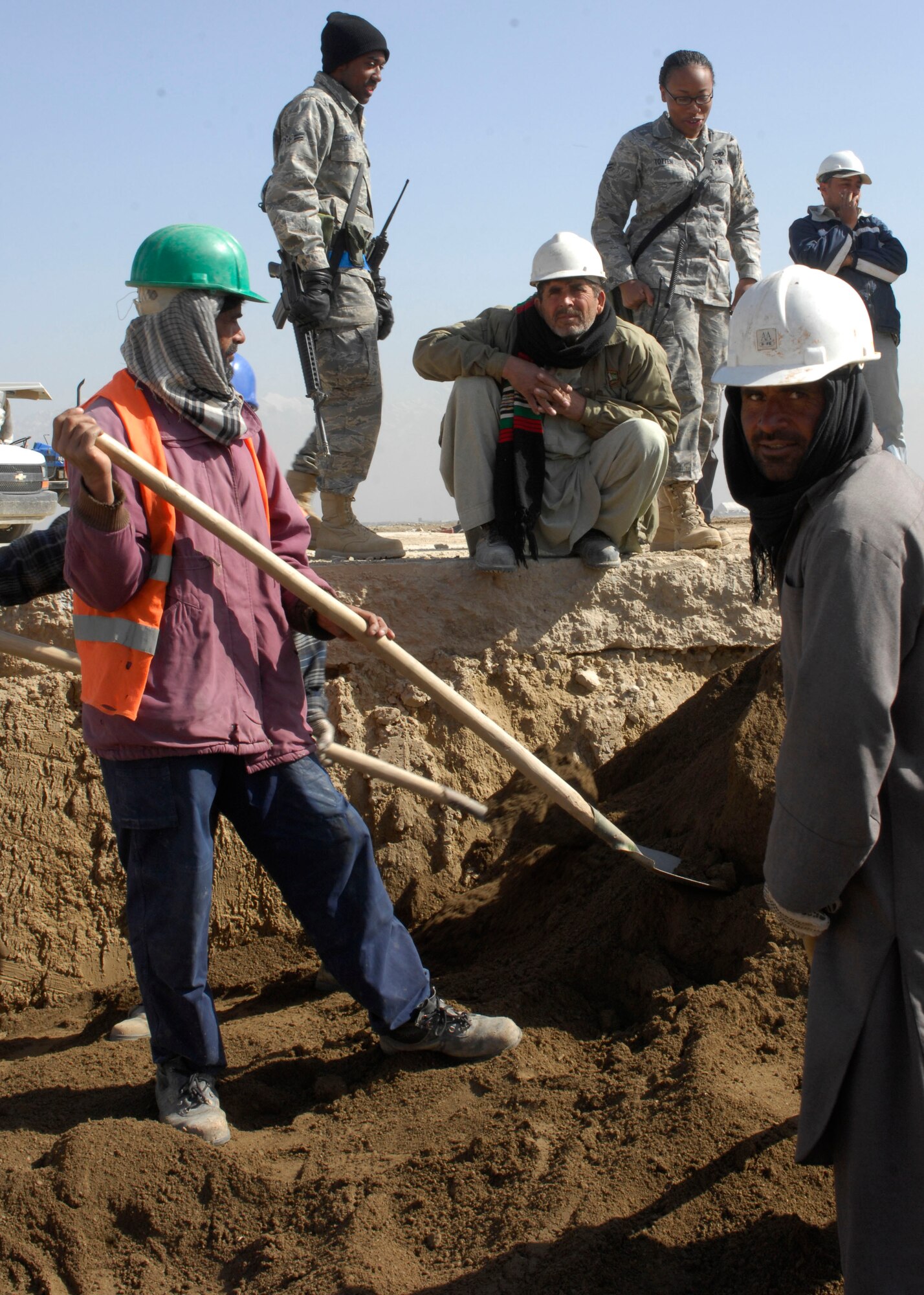 Airman 1st Class Corey Gleynn, 455th Expeditionary Civil Engineer Squadron force protection flight, and Airman 1st Class Linae Totten, 455th ECES FP flight, escort third country nationals and local workers digging a ditch for fuel line installation at Bagram Air Field, Afghanistan, March 12. There are approximately 70 Airmen that escort anywhere from 75 to 100 TCN's on any given day. FP Airmen are currently on a four-month deployment and are in charge of all TCN workers in secure areas. Airmen Totten is deployed from Barksdale Air Force Base, La., and hales from Phenix, Ala. Airmen Gleynn is deployed from RAF Lakenheath, England, and hales from Barksdale AFB, La. (U.S. Air Force photo/ Senior Airman Erik Cardenas)(Released)