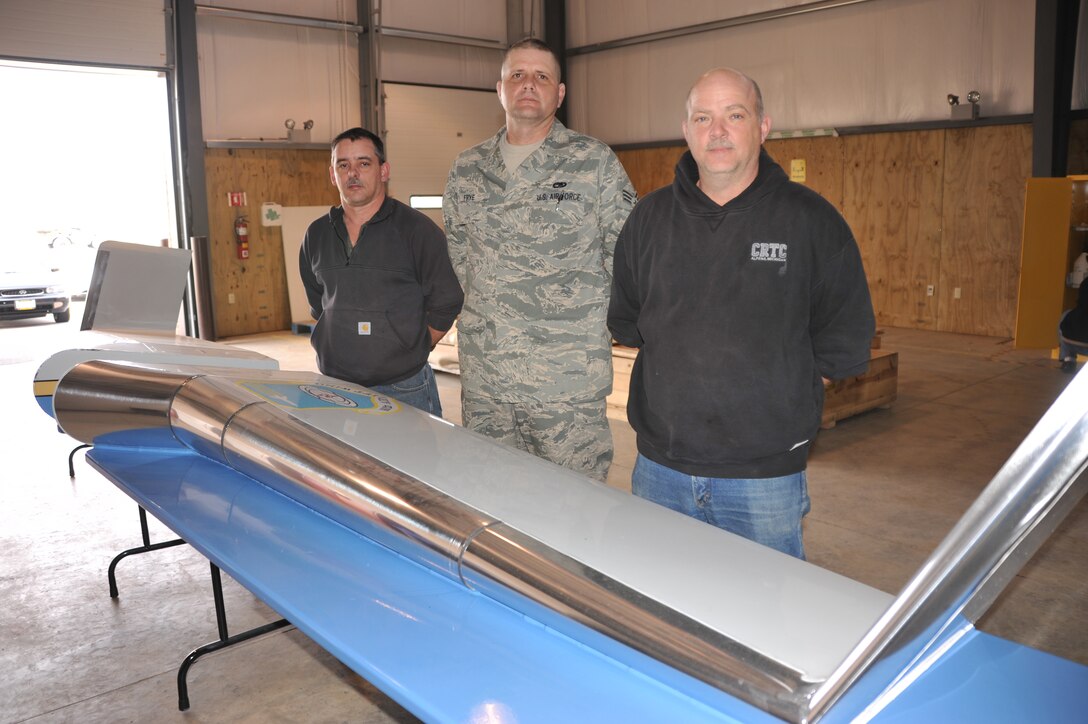 Master Sgt. Mike Jenkins, Senior Airman Chris Frye and Master Sgt. Jimmie Evans stand next to the C-40 replica wings they helped create. Photo by Tech. Sgt. Dan Oliver