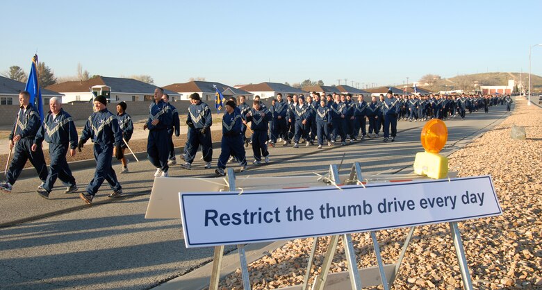 Edwards Airmen walk along FitzGerald Boulevard March 13 to read some signs regarding network security in conjunction with the formation run. The 95th Communications Group hosted a series of events to ensure network security awareness. (U.S. Air Force photo/Senior Airman Julius Delos Reyes)