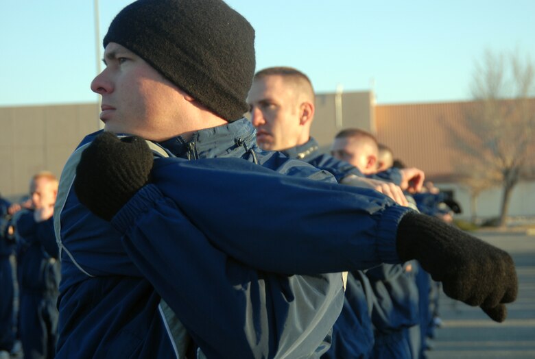 Tech. Sgt. Casey Schoettmer, 412th Aircraft Maintenance Squadron F-35 Joint Strike Fighter egress systems noncommissioned officer in charge, with other Airmen, stretches prior to a base formation run March 13 at the Base Exchange parking lot. Edwards Airmen ran more than 2.4 miles to promote fitness and esprit de corps. (U.S. Air Force photo/Senior Airman Julius Delos Reyes)