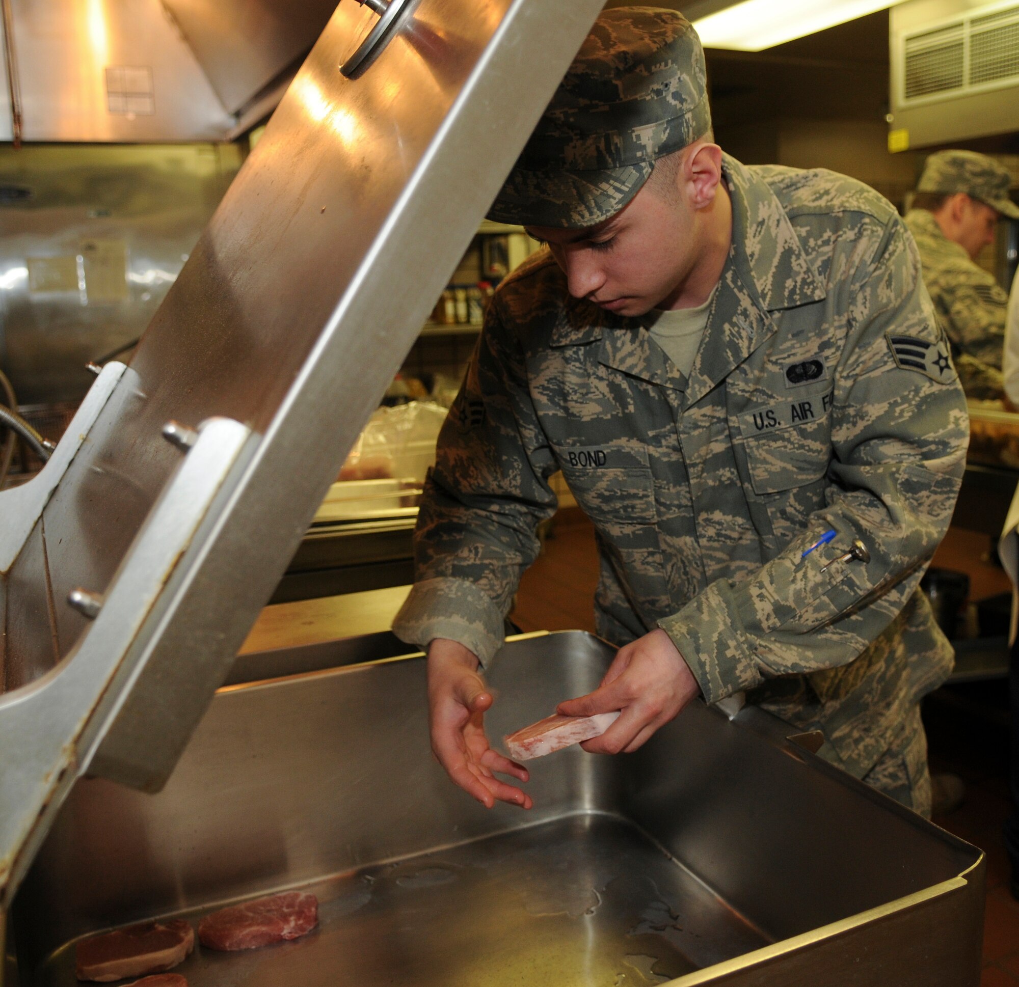 Senior Airman Jason Bond, 354th Force Support Squadron, places pork chops in the tilt grill March 12, 2009, Eielson Air Force Base, Alaska. The tilt grill allows Airman Bond to cook several pork chops in a short amount of time. (U.S. Air Force photo/Airman 1st Class Laura Max)