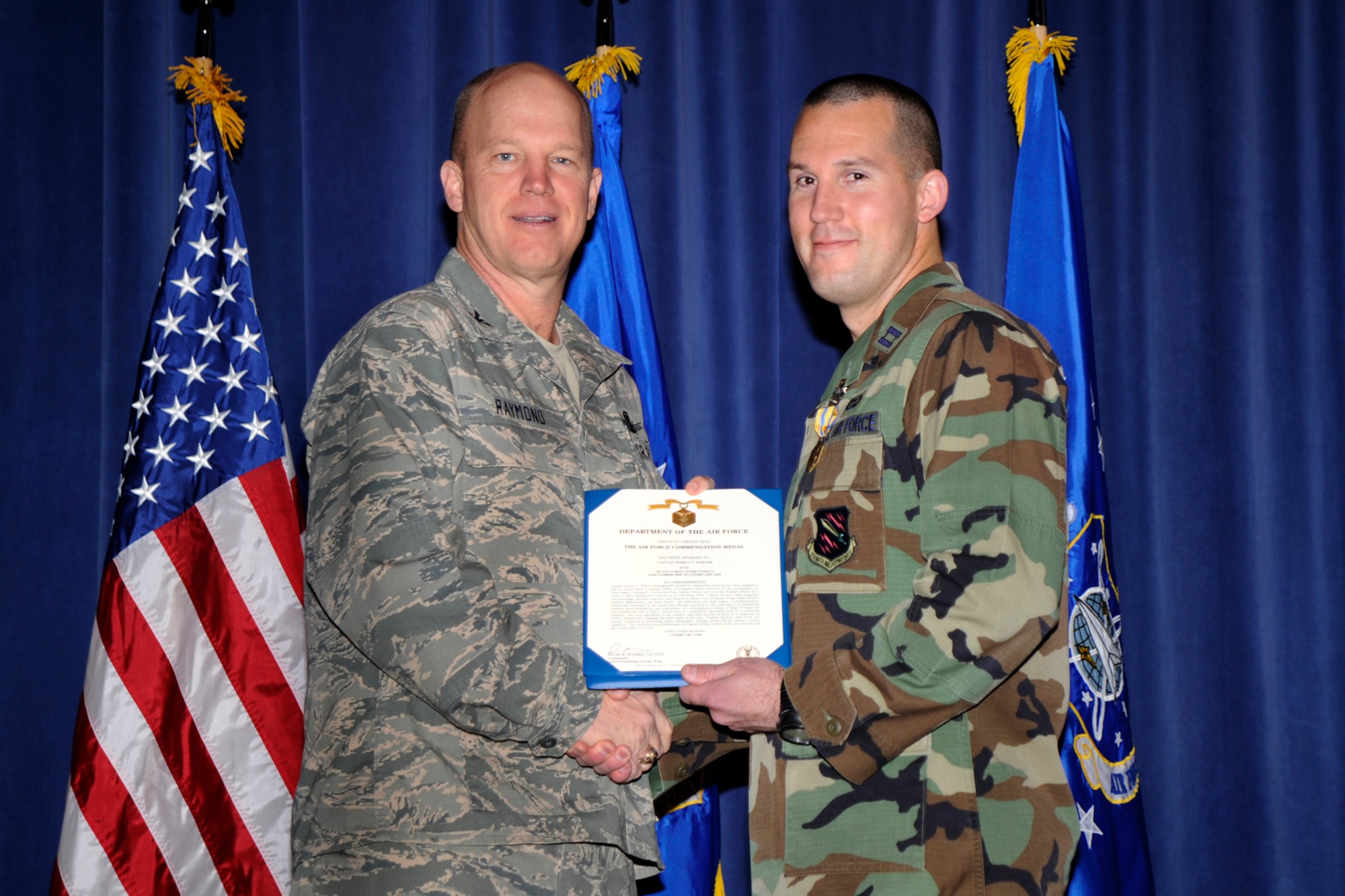 Col. Jay Raymond, Wing Commander, 21st Space Wing, congratulates Captain Joshua Werner after he was awarded the Air Force Commendation Medal during the March 10 Commander's Call. (Air Force photo by Craig Denton)
