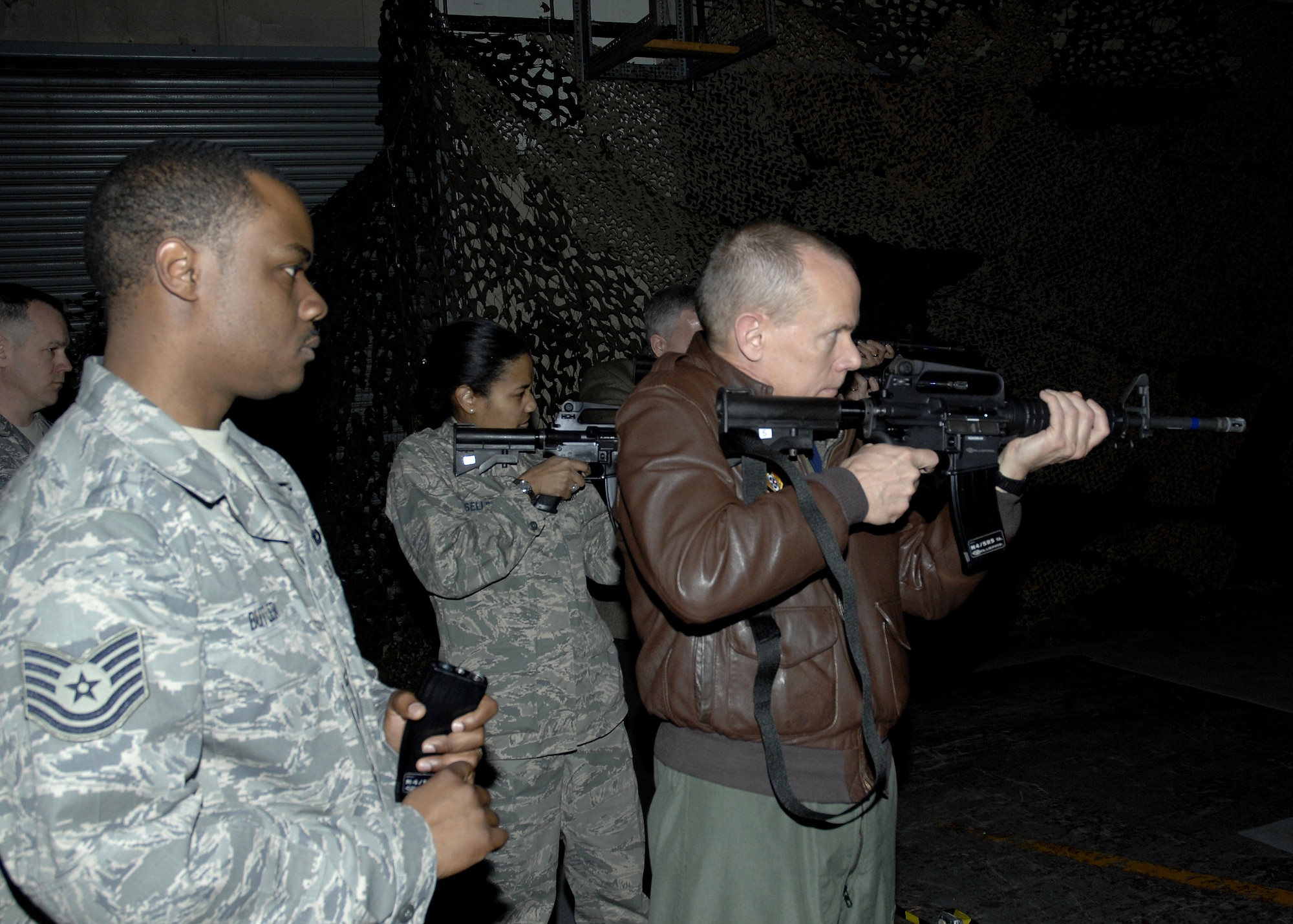 General Donald J. Hoffman, takes aim with an M-4 carbine during a scenario on the Firearms Training Simulator in Janurary at Wright-Patterson Air Force Base, Ohio. Looking on is the training director, Tech. Sgt. Bryant Butler of the 88th Security Forces Squadron. General Hoffman is the commander of Air Force Materiel Command. (U.S. Air Force photo) 
