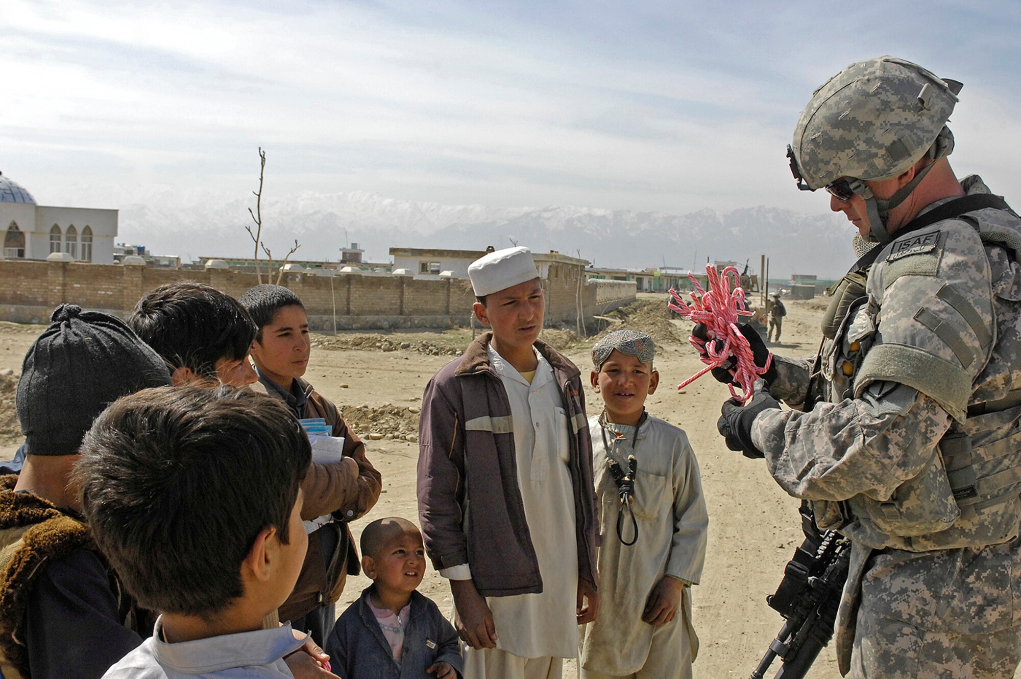 Air Force Master Sgt. Todd Davis, Kapisa/Parwan Provincial Reconstruction Team civil engineer and pay agent, hands out candy canes to local children March 14 in Mahmood Raqi, Afghanistan. More than a dozen Soldiers, Airmen and civilian translators assigned to the PRT at Bagram Air Field convoyed March 14 to several construction sites to monitor progress made by local contractors hired to improve local infrastructure. Sergeant Davis, who is deployed from Whiteman Air Force Base, Mo., spoke with the local foreman to see if there were any construction site problems or pay concerns with local workers. Sergeant Davis, a Troy, Ill.-native, is one of 24 Airmen assigned to the PRT filling joint expeditionary taskings. (Air Force photo by Staff Sgt. Jason Lake)