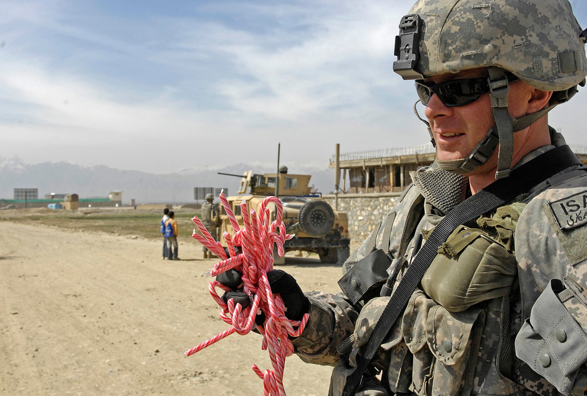 Air Force Master Sgt. Todd Davis, Kapisa/Parwan Provincial Reconstruction Team civil engineer and pay agent, grabs a handful of candy canes to hand out to local children in Mahmood Raqi, Afghanistan, March 14. More than a dozen Soldiers, Airmen and civilian translators assigned to the PRT at Bagram Air Field convoyed March 14 to several construction sites to monitor progress made by local contractors hired to improve local infrastructure. Sergeant Davis, who is deployed from Whiteman Air Force Base, Mo., spoke with the local foreman to see if there were any construction site problems or pay concerns with local workers. Sergeant Davis, a Troy, Ill.-native, is one of 24 Airmen assigned to the PRT filling joint expeditionary taskings. (U.S. Air Force photo by Staff Sgt. Jason Lake)