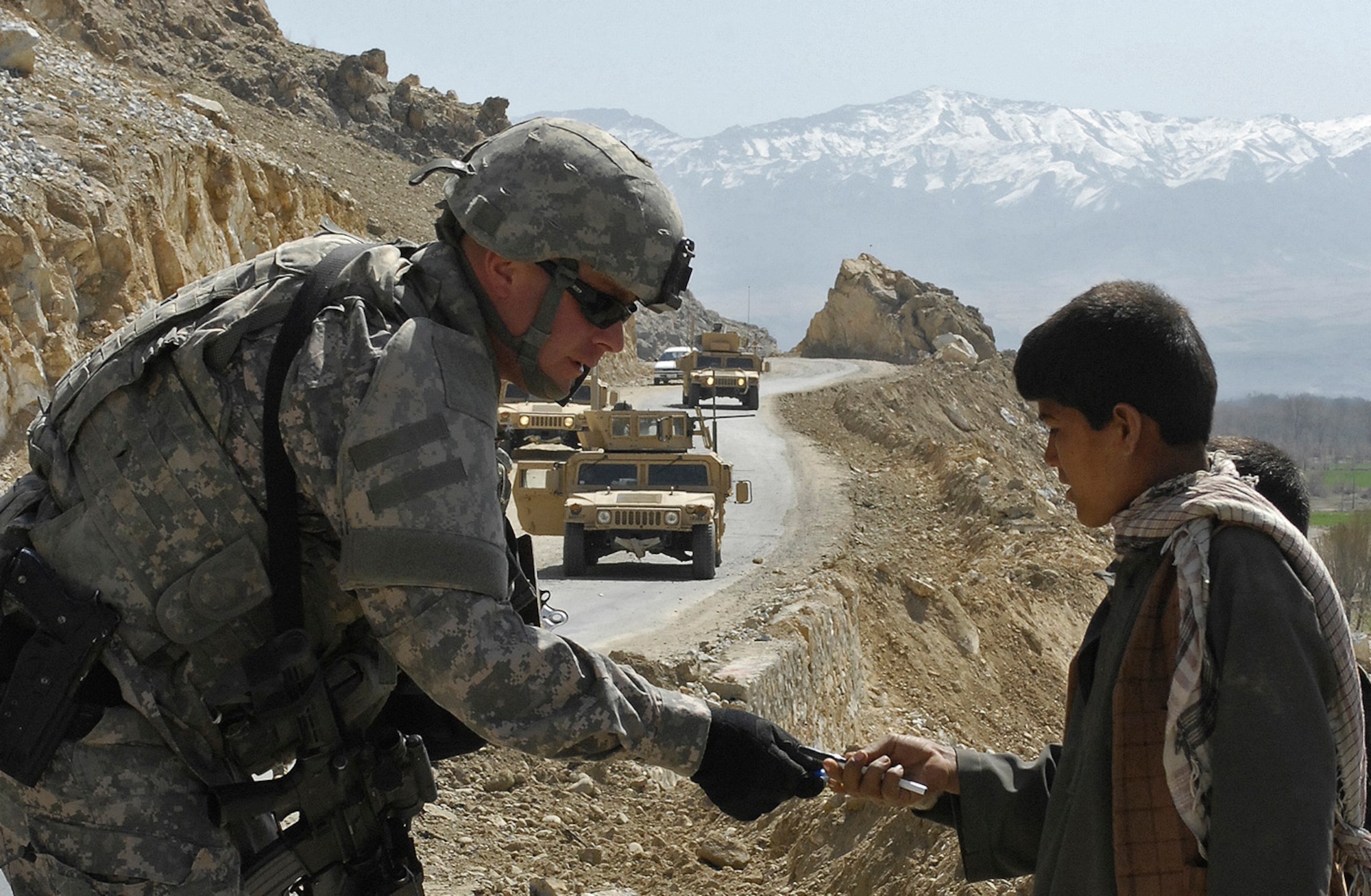 Air Force Master Sgt. Todd Davis, from the Kapisa/Parwan Provincial Reconstruction Team civil engineer and pay agent, hands out pens to local children at a gravel crushing plant construction site near Mahmood Raqi, Afghanistan, March 14. More than a dozen Soldiers, Airmen and two civilian translators from the PRT at Bagram Air Field convoyed to several construction sites to monitor progress made by local contractors hired to improve local infrastructure. Sergeant Davis, who is deployed from Whiteman Air Force Base, Mo., spoke with the local foreman to see if there were any construction site problems or pay concerns with local workers. Sergeant Davis, a Troy, Ill.-native, is one of 24 Airmen assigned to the PRT filling joint expeditionary taskings. (U.S. Air Force photo by Staff Sgt. Jason Lake)