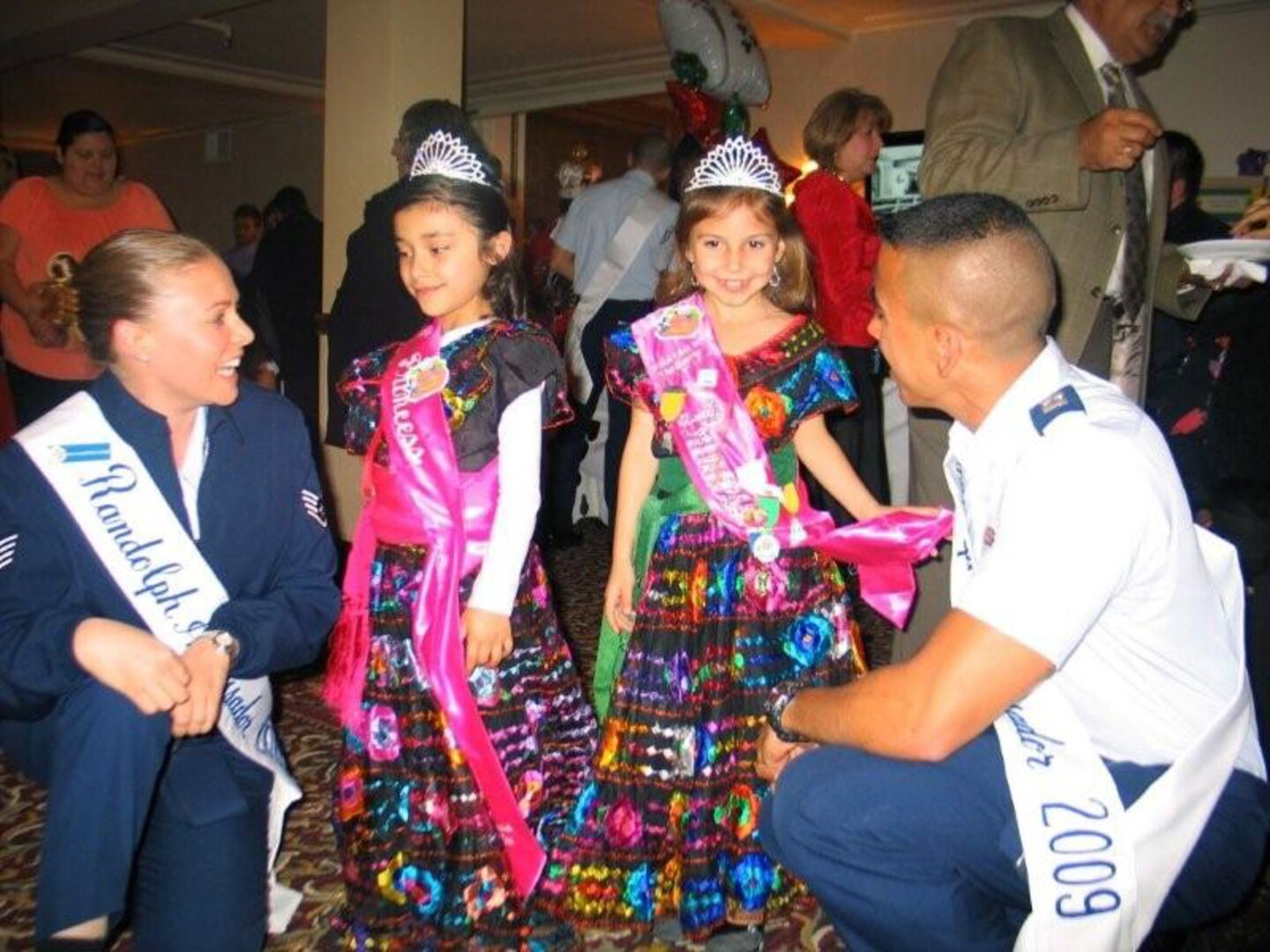 Randolph Ambassadors Staff Sgt. Courtney Linde and Capt. Carlos Ferrer visit with two young dancers who will perform at the "Pinatas in the Barrio" pre-Fiesta celebration during the Fiesta Commission Media Day at St. Anthony's hotel on March 12.