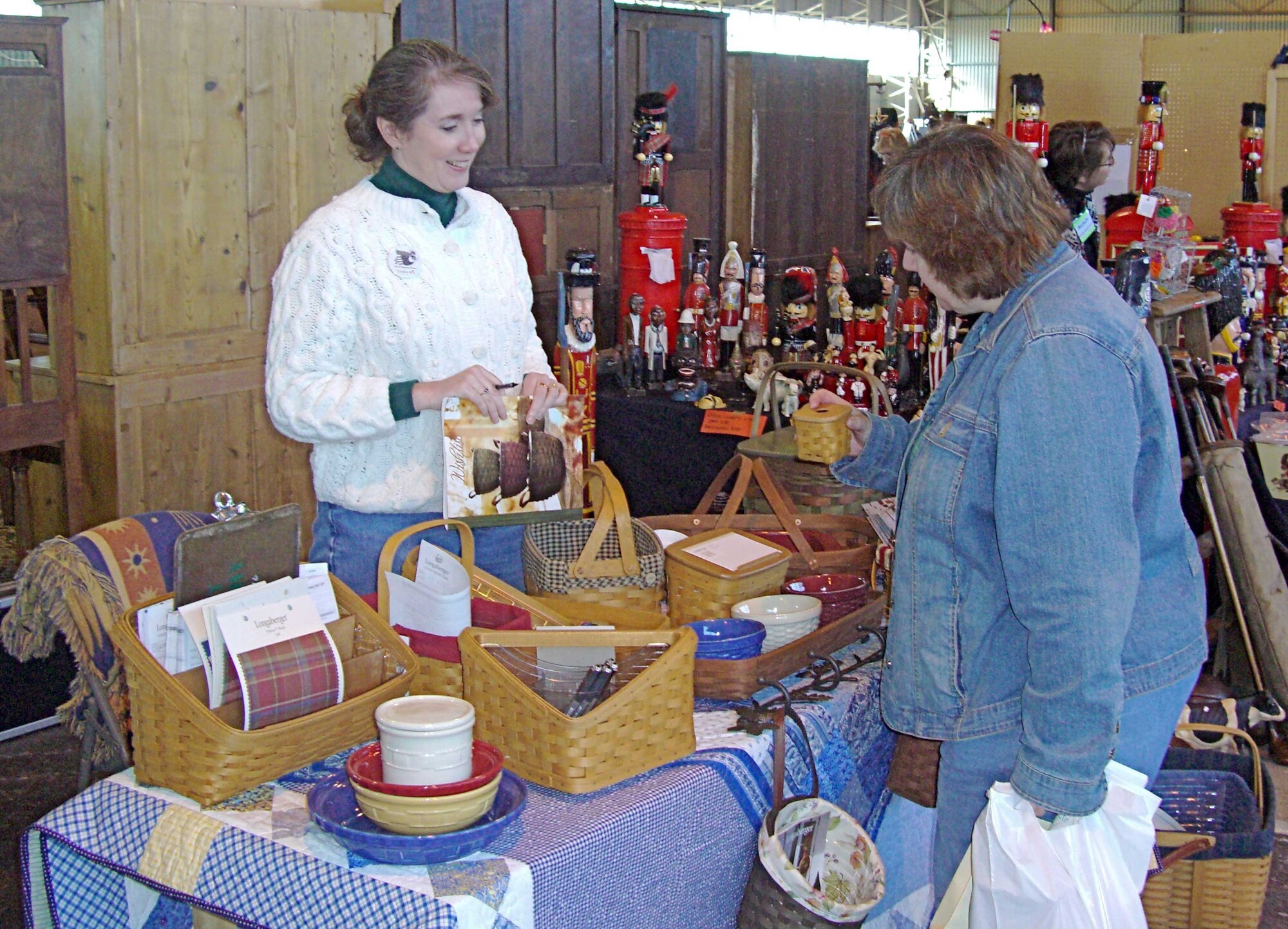 A vendor shows a customer a hand-woven basket at the annual Molesworth Bazaar. The basket display was just one of the over fifty vendors at the event to be held Friday through Saturday March 27 - 29. Proceeds from the bazaar support charitable work of the Tribase Officer and Civilian Spouses Club and the Enlisted Spouses Club. The two oganizations jointly sponsor the annual event. (USAF Photo by Peter Park)