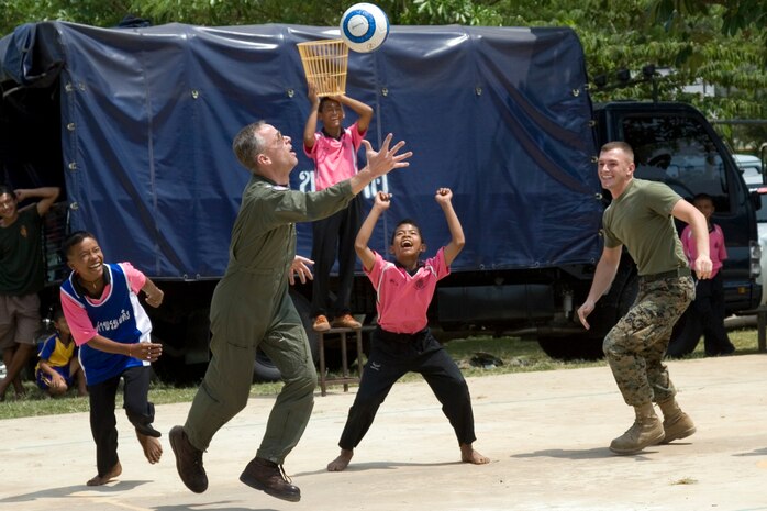 U.S. service members play basketball with children during a visit by Cope Tiger participants to Ban Lan Nang Keaw elementary school in Ban Lan Nang city as part of the humanitarian efforts of exercise Cope Tiger 2009 taking place in Korat, Thailand March 16. Since the school basketball court has no basketball goals students stand on a box holding a bucket in their hands for goals.