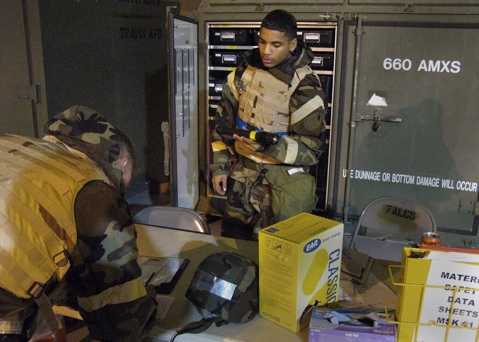 TRAVIS AIR FORCE BASE, Calif. -- Airman Jose M. Omana, 60th Maintenance Squadron, issues a flashlight to a maintainer during CRISIS LOOK 09-02. Airmen from 60th and 349th Air Mobility Wings here, and the 89th Airlift Wing, Andrews Air Force Base, Md., blended into one team March 2 through 8 to practice fighting against a chemical-weapons equipped enemy. The Operational Readiness Exercise also tested the units' processes for deploying troops and cargo to an overseas contingency. This was the first of three exercises to prepare the Wings for a graded Operational Readiness Inspection in October. (U.S. Air Force photo / Maj. Robert Couse-Baker)